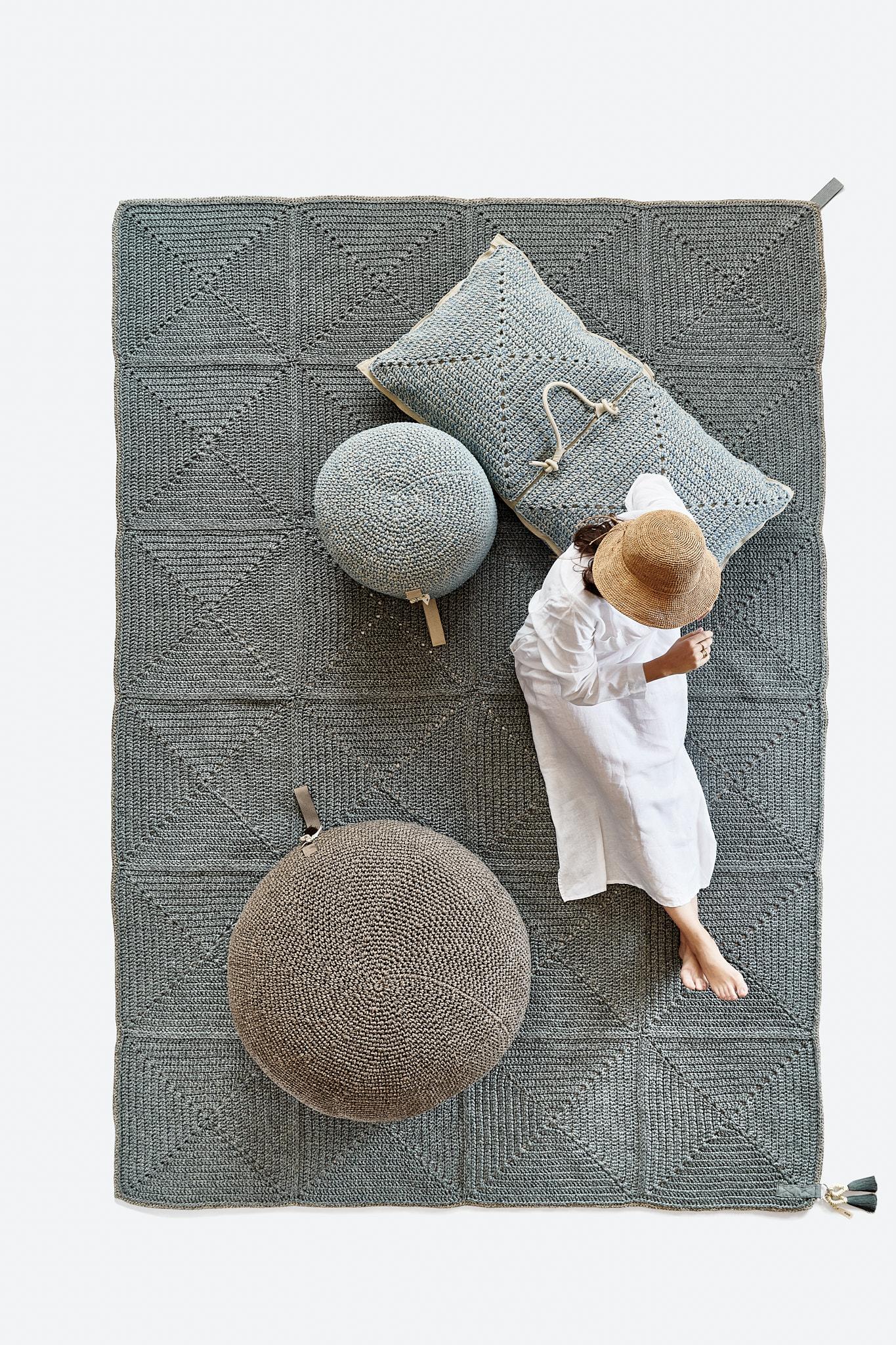 The Classic crochet granny square takes a contemporary twist in this outdoor rug. Large squares form the rug, framed with bespoke webbing. Handmade from UV protected bespoke iota yarn in earth tones, the textile is soft, yet durable and suitable for