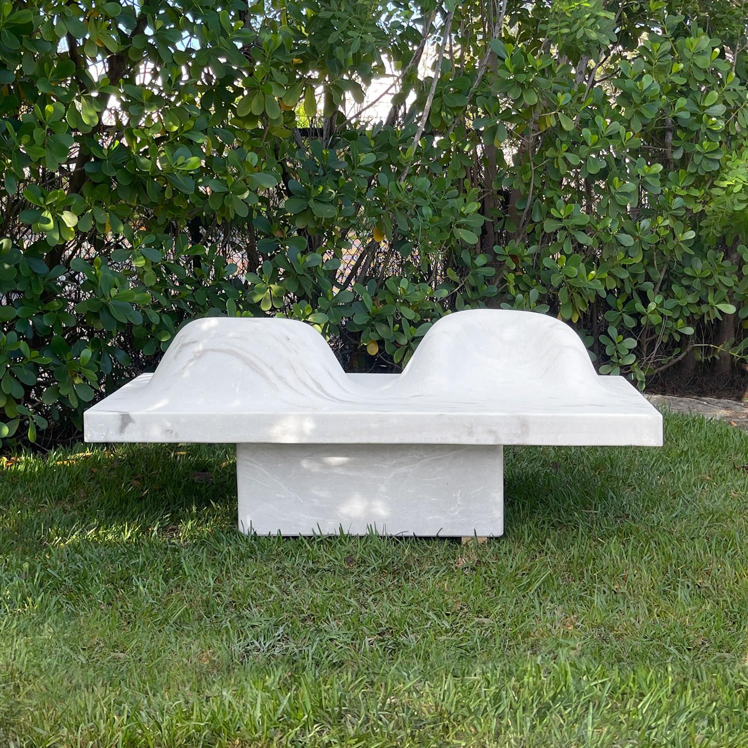 Eine zeitgenössische, modern gestaltete Gartenbank, die von Hand aus einem einzigen Block weißen Marmors mit feiner grauer Maserung gehauen wurde. Die dicke rechteckige Sitzfläche wird durch einen massiven Marmorblock erhöht. Die Platte ist durch