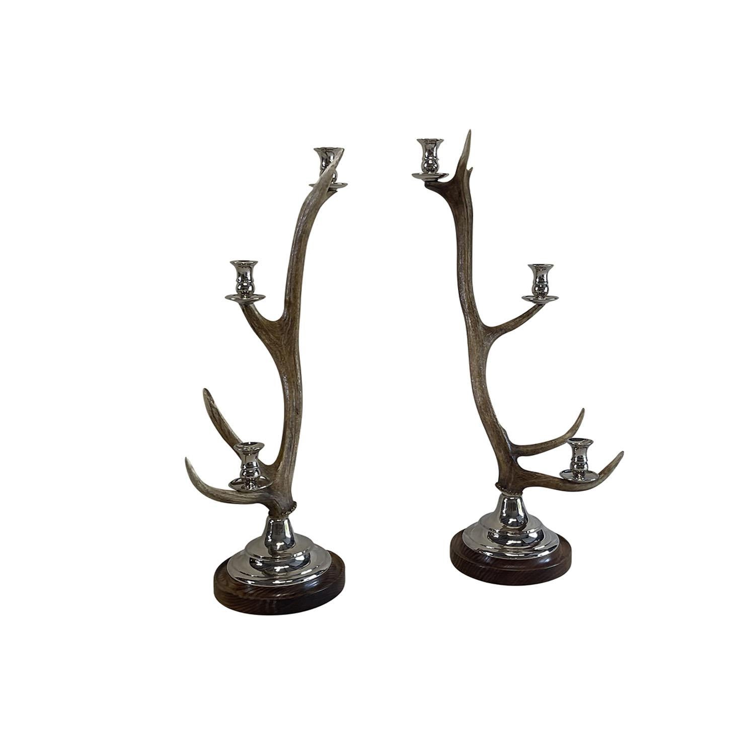 A pair of tall Belgian candle holders made of faux antlers, in good condition. Each has three candle holder cups made of nickel. These impressive candle holders are raised and sit on circular bases. Wear consistent with age and use. Circa 21st