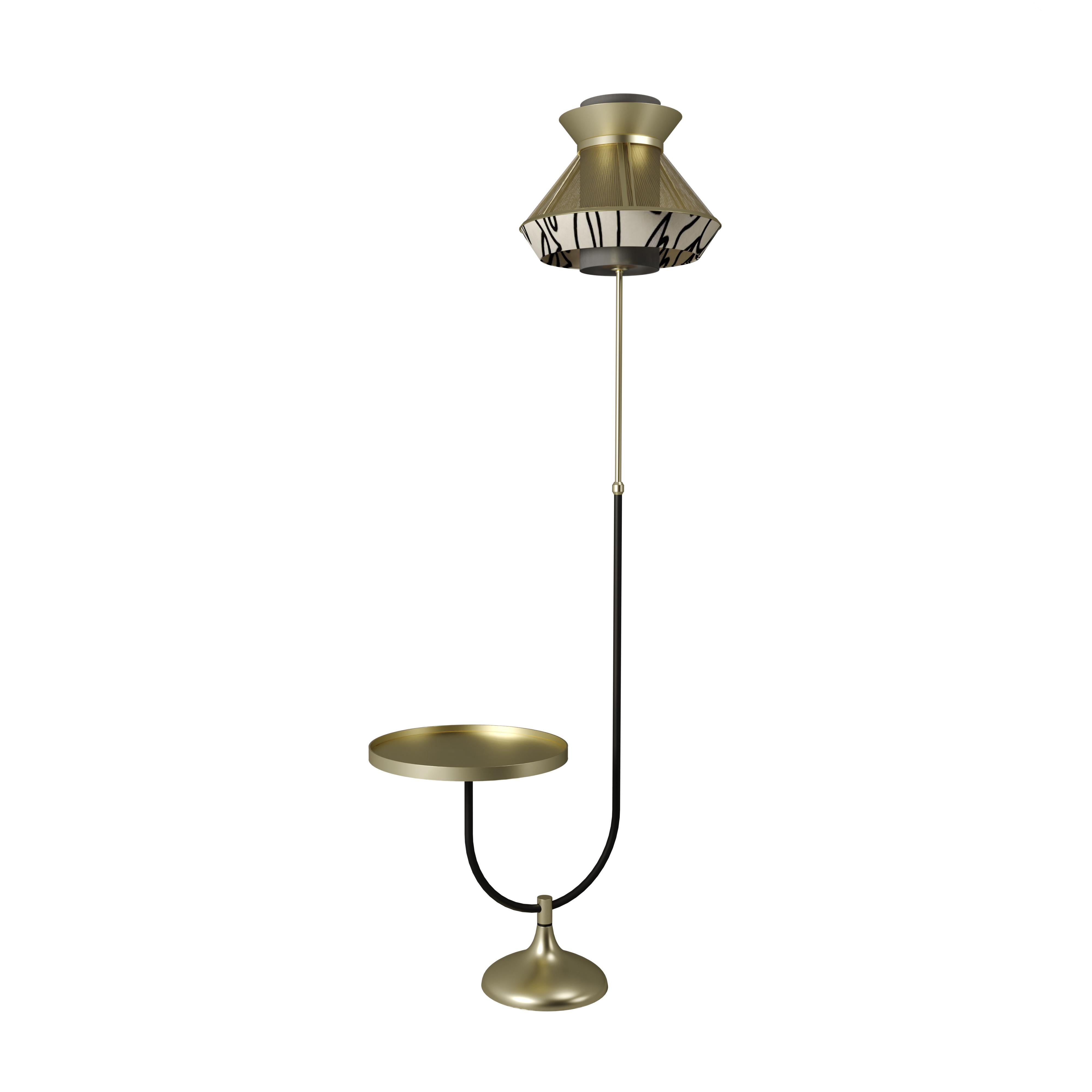 Contemporary, supreme, and always chic, the Bennett floor lamp with a brushed brass table attached is a piece to create a statement. The Bennett table floor standing light features a lampshade combination of brass and an abstract black and with