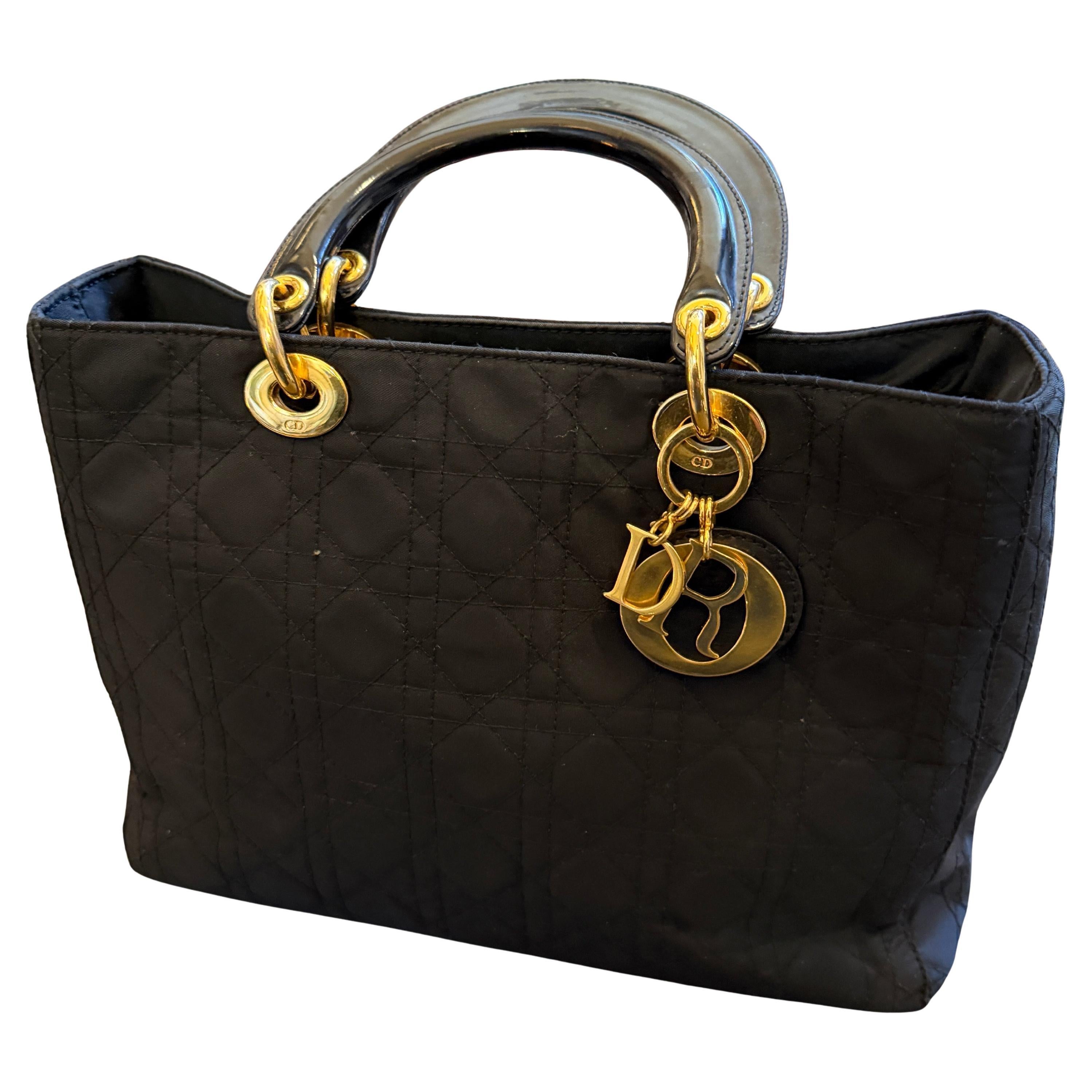 This is an excellent example of the iconic Lady Dior tote bag, a signature piece from Christian Dior, dating from the 21st Century. Crafted in black quilted fabric, the bag features the distinctive Cannage stitching pattern, giving it its classic,