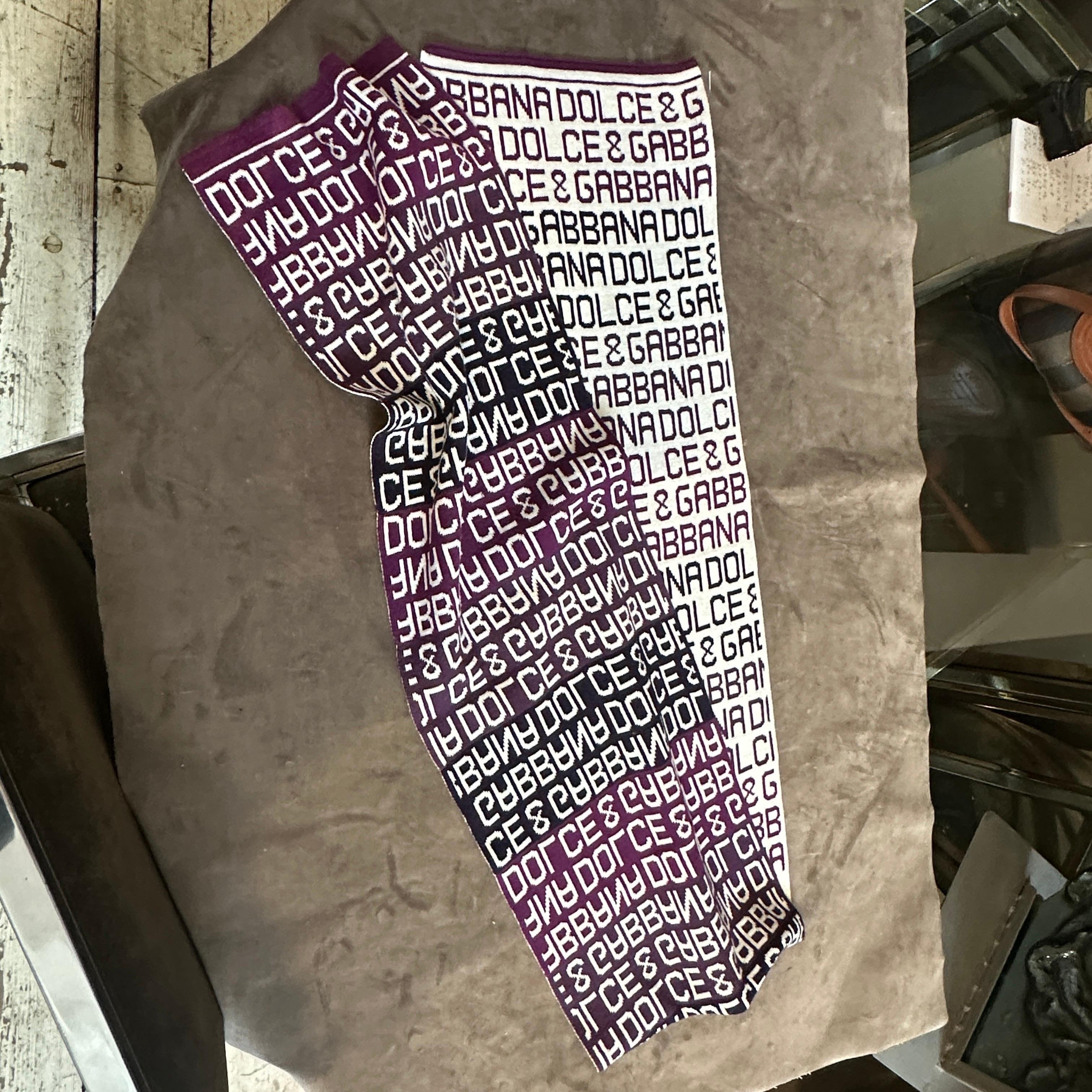 Questo straordinario foulard Dolce & Gabbana del XXI secolo è un accessorio alla moda caratterizzato da un audace motivo a logo continuo nei colori bordeaux, nero e bianco. La sciarpa presenta l'iconico marchio 