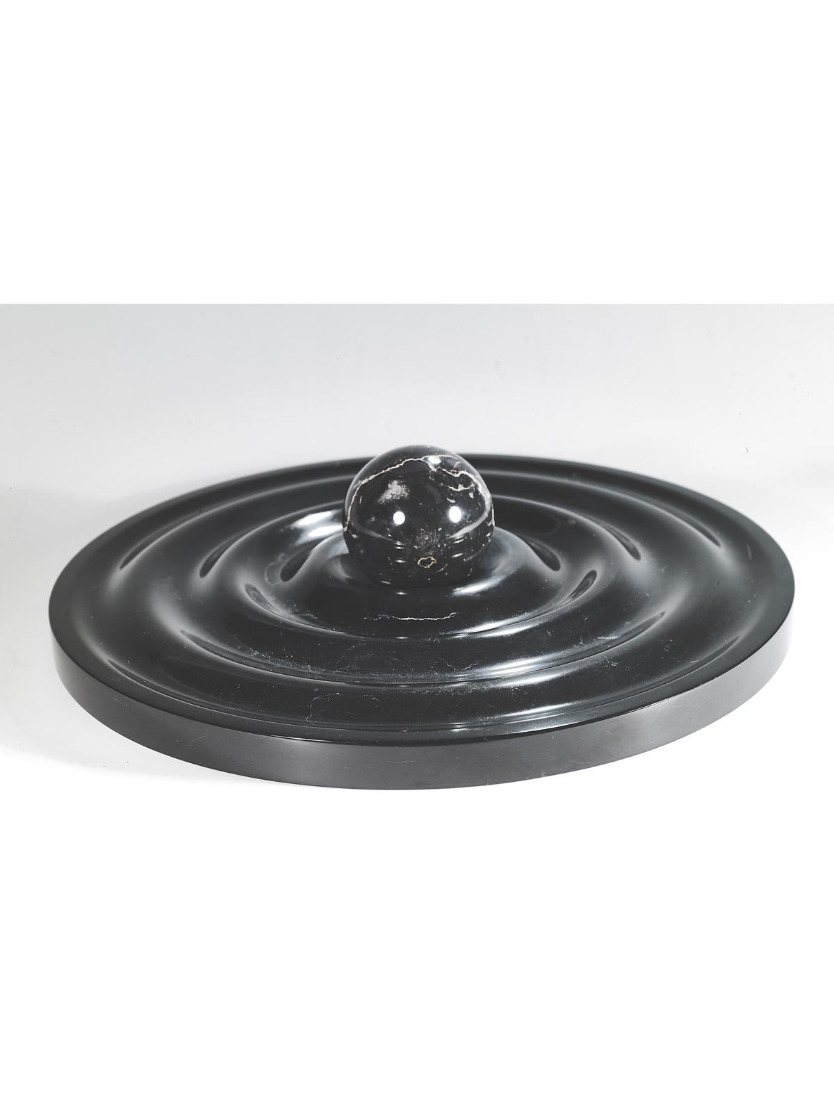 Centrotavola in marmo progettato da Alessandro Gorla nell'anno 2020.
 Disponibile in tre diversi materiali Bianco Carrara, Travertino Rosso, Nero Belgio con finitura lucida. 
 Dimensioni: Diametro 40 cm x 8 cm di altezza.