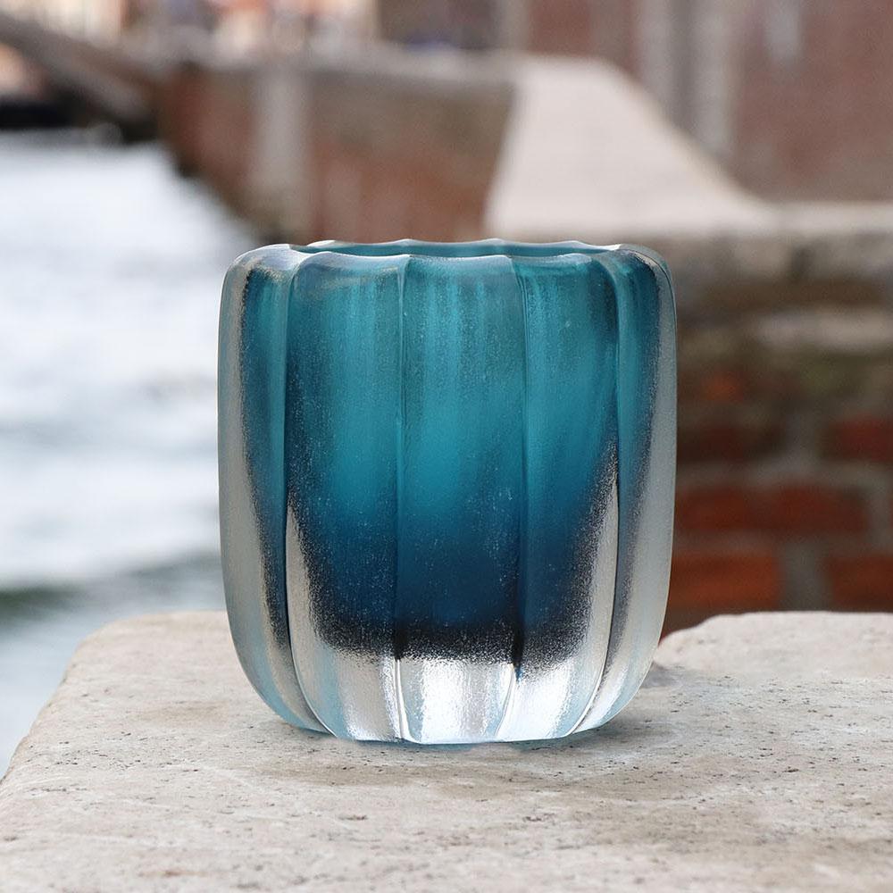 The name Rullo evokes the act of rolling the heated glass on the blow pipe. This small vase is first shaped by blowing the molten glass and further modelled by carving the surface once cooled. The vibrations of the light on the etched surface are