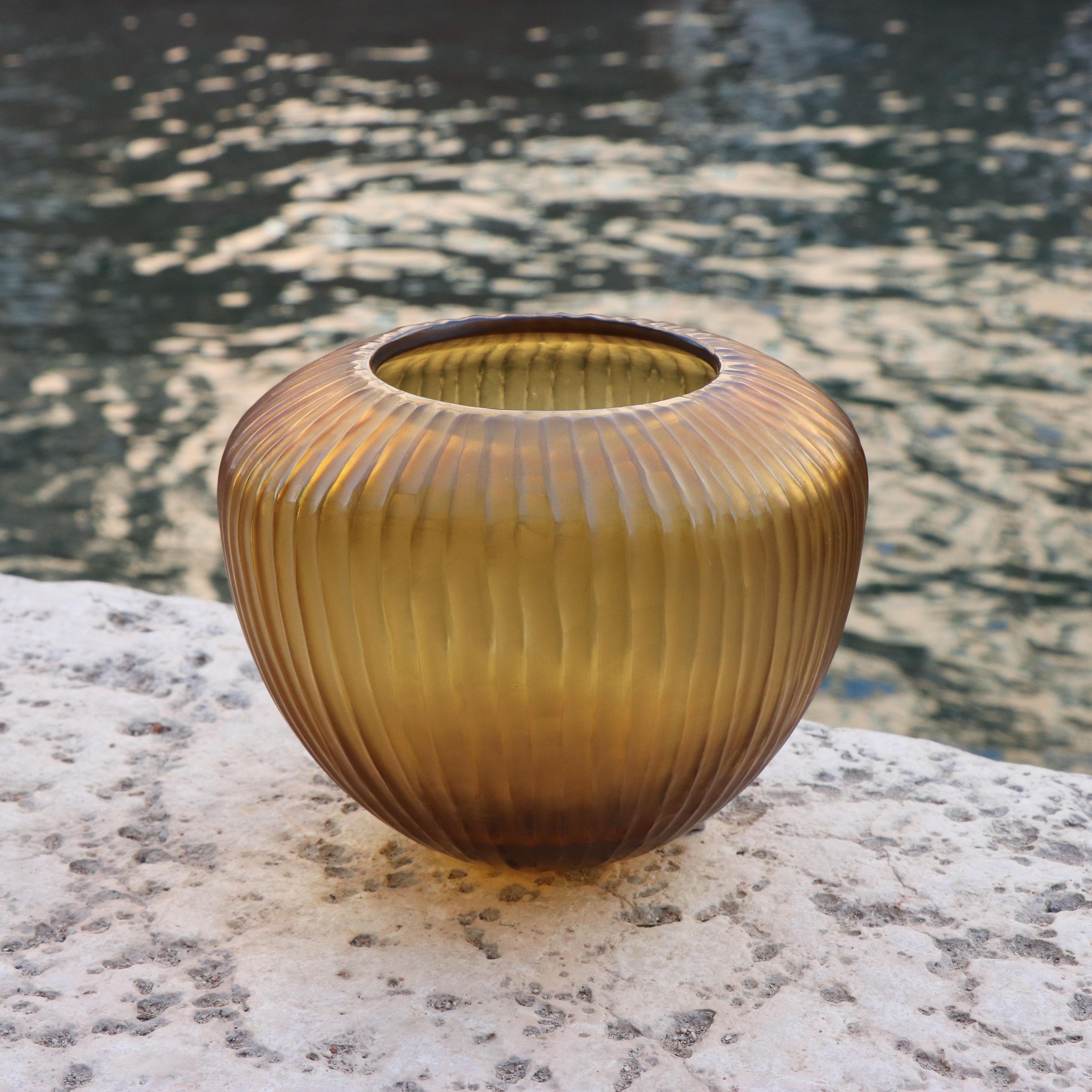 Inspired by the ancient amphorae, this vase resembles the elongated form of a drop, which in Italian translates as Goccia. Following the blowing process the vase is engraved and polished producing a vibrant faceted surface.

This vase is