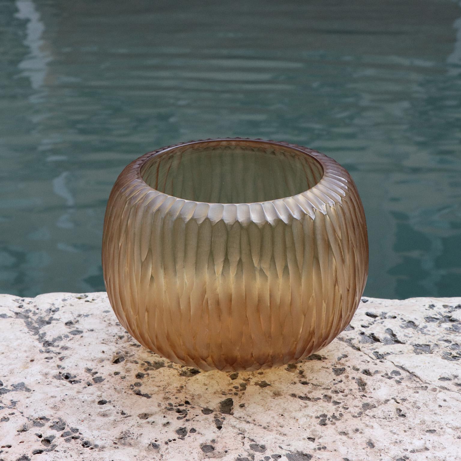 Playfully named Puffo this vase has a round ‘pouf-like’ shape. To achieve the desired form and dimensions the molten glass is first mouth blown. Once cooled the surface is transformed by a laborious cold carving process called ‘molatura’ lending the