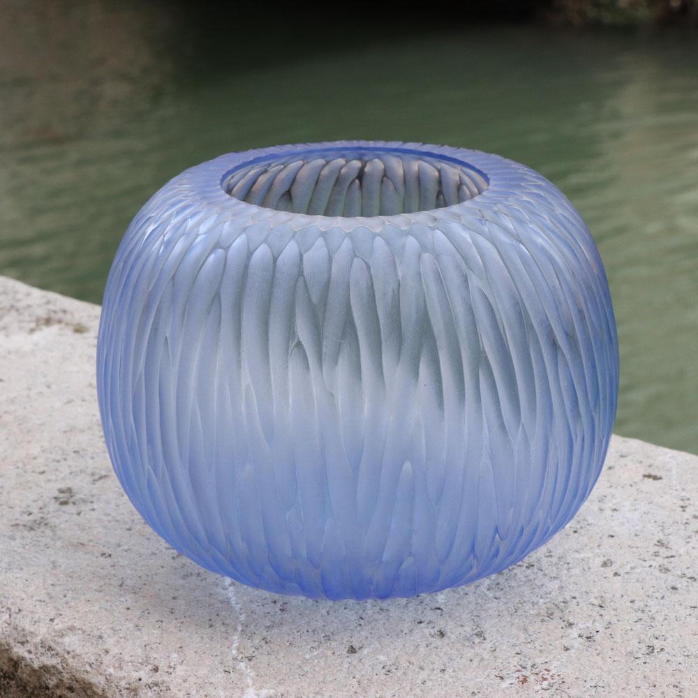 Playfully named Puffo this vase has a round ‘pouf-like’ shape. To achieve the desired form and dimensions the molten glass is first mouthblown. Once cooled the surface is transformed by a laborious cold carving process called ‘molatura’ lending the