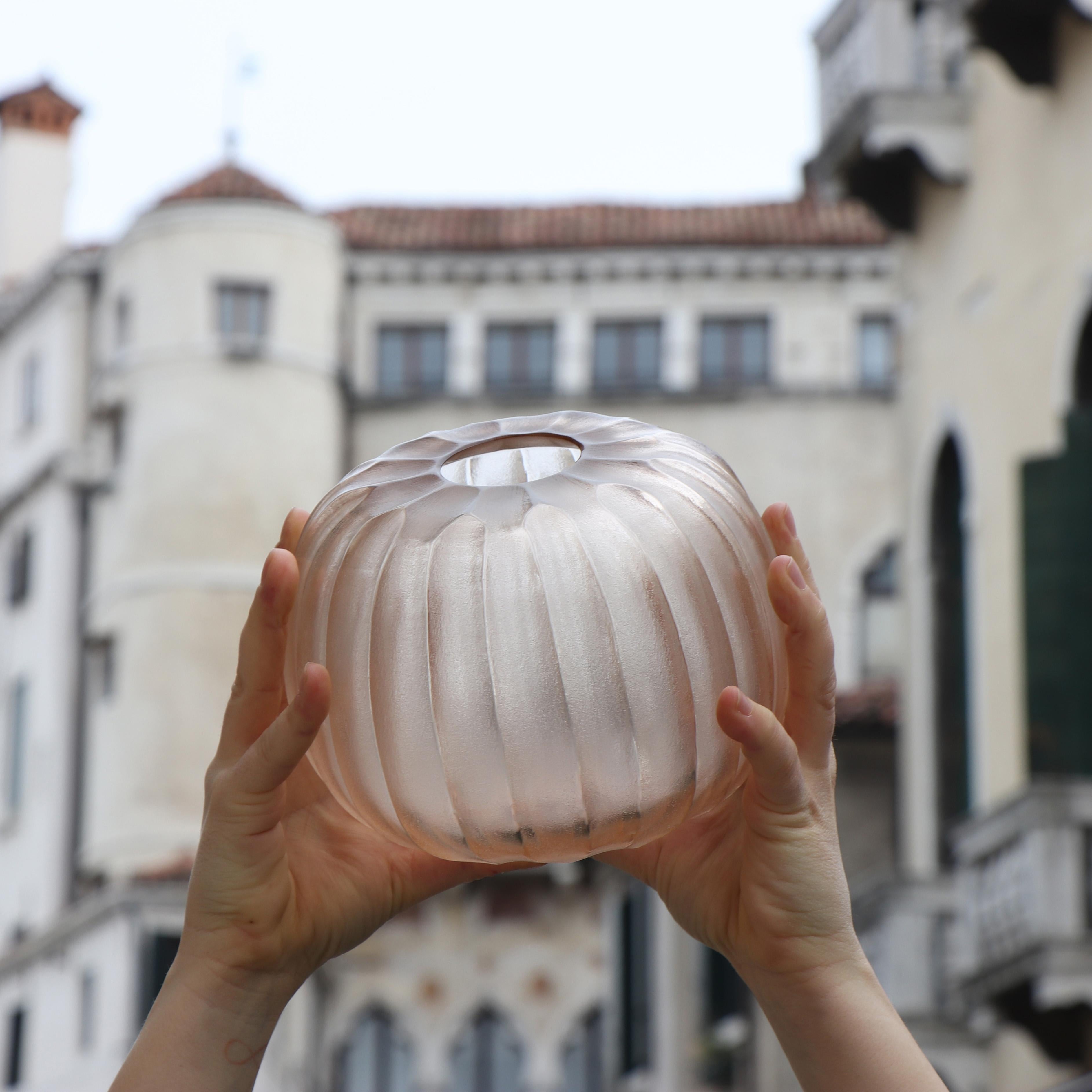 The melted glass is first blown in the heat of the furnace and shaped into a round vase with a small opening. Once solid the glass is cold carved to produce the linear cuts which mark its surface reminding us of the shell of a sea urchin,