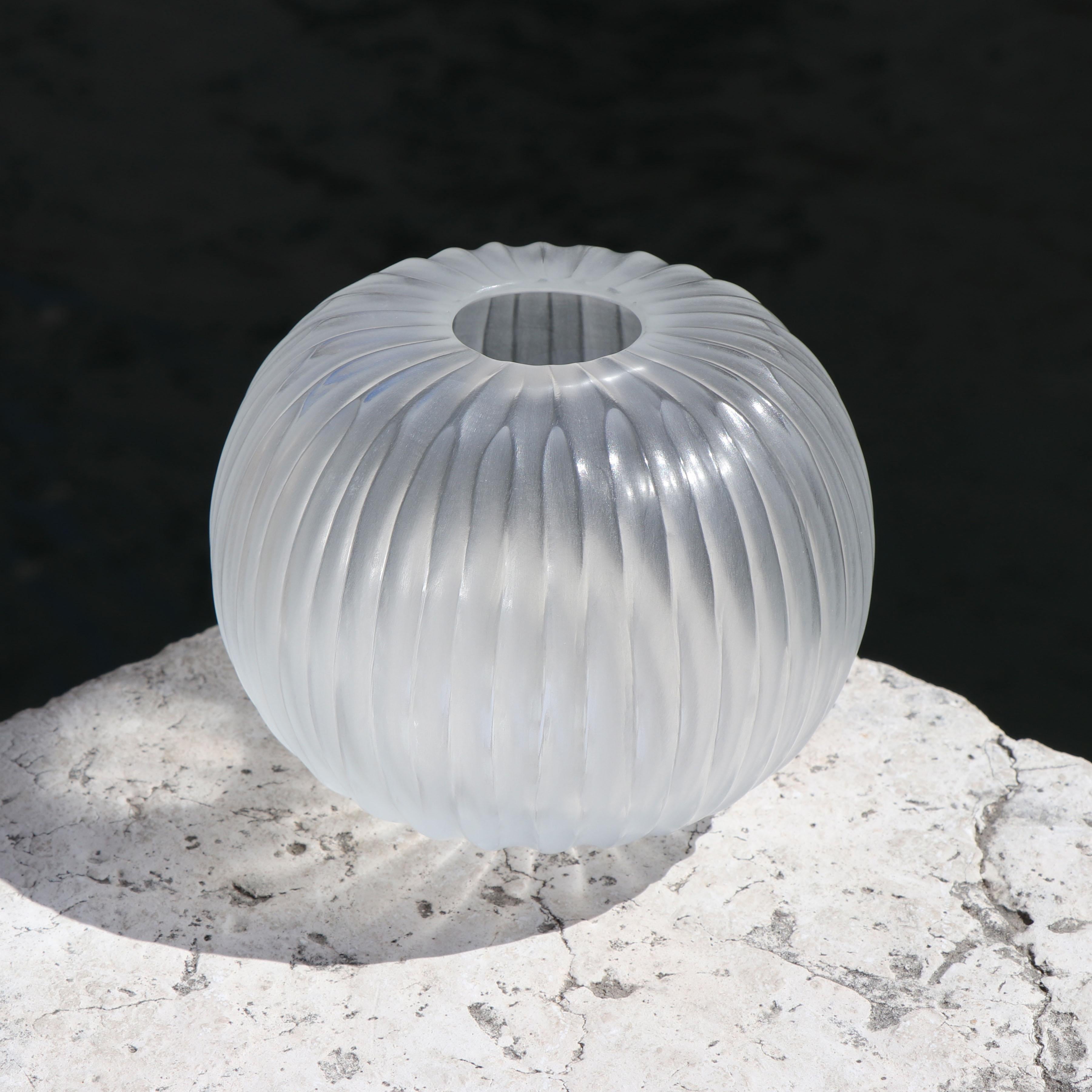 The melted glass is first blown in the heat of the furnace and shaped into a round vase with a small opening. Once solid the glass is cold carved to produce the linear cuts which mark its surface reminding us of the shell of a sea urchin, Riccio.