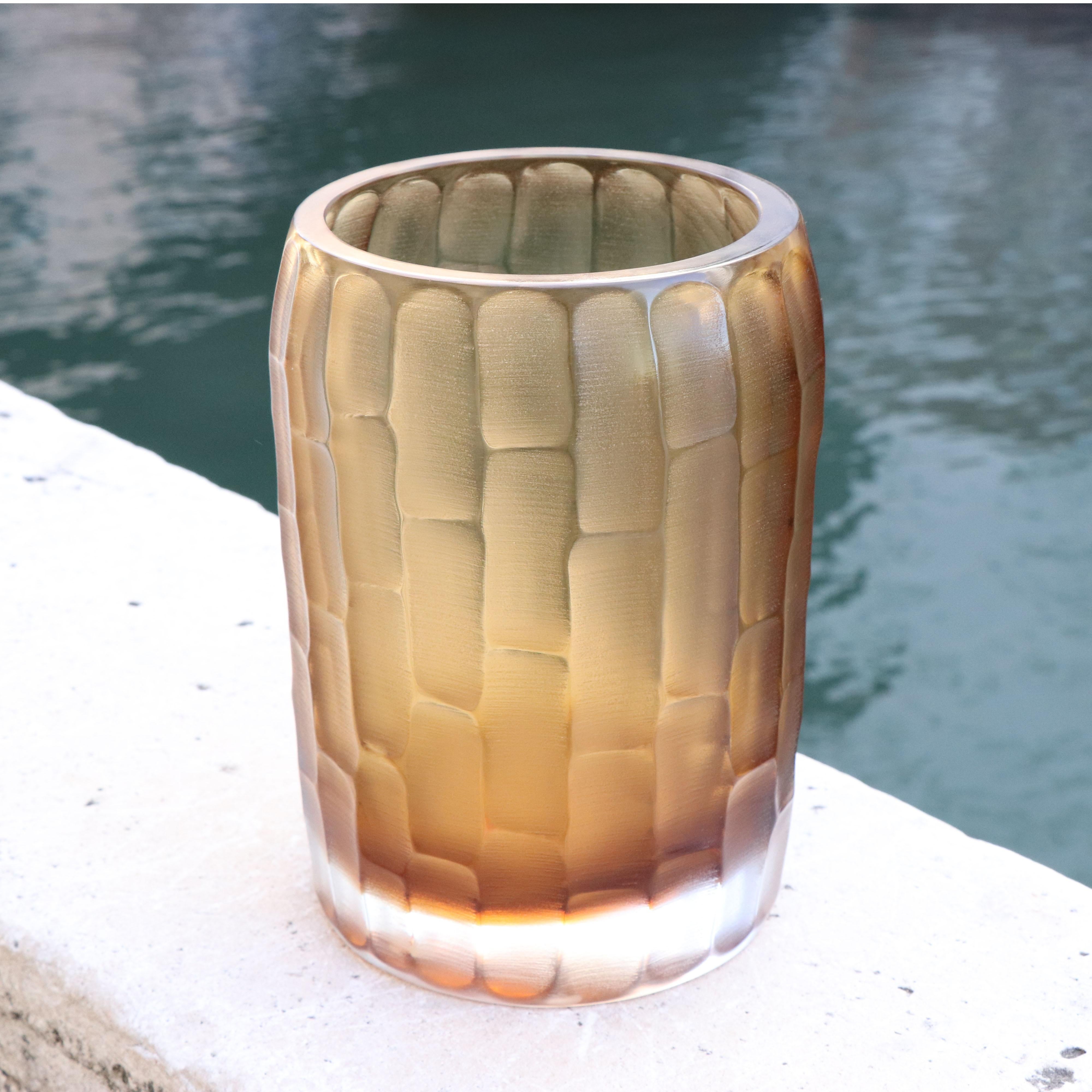 The name Rullo evokes the act of rolling the heated glass on the blow pipe. This small vase is first shaped by blowing the molten glass and further modelled by carving the surface once cooled. The vibrations of the light on the etched surface are