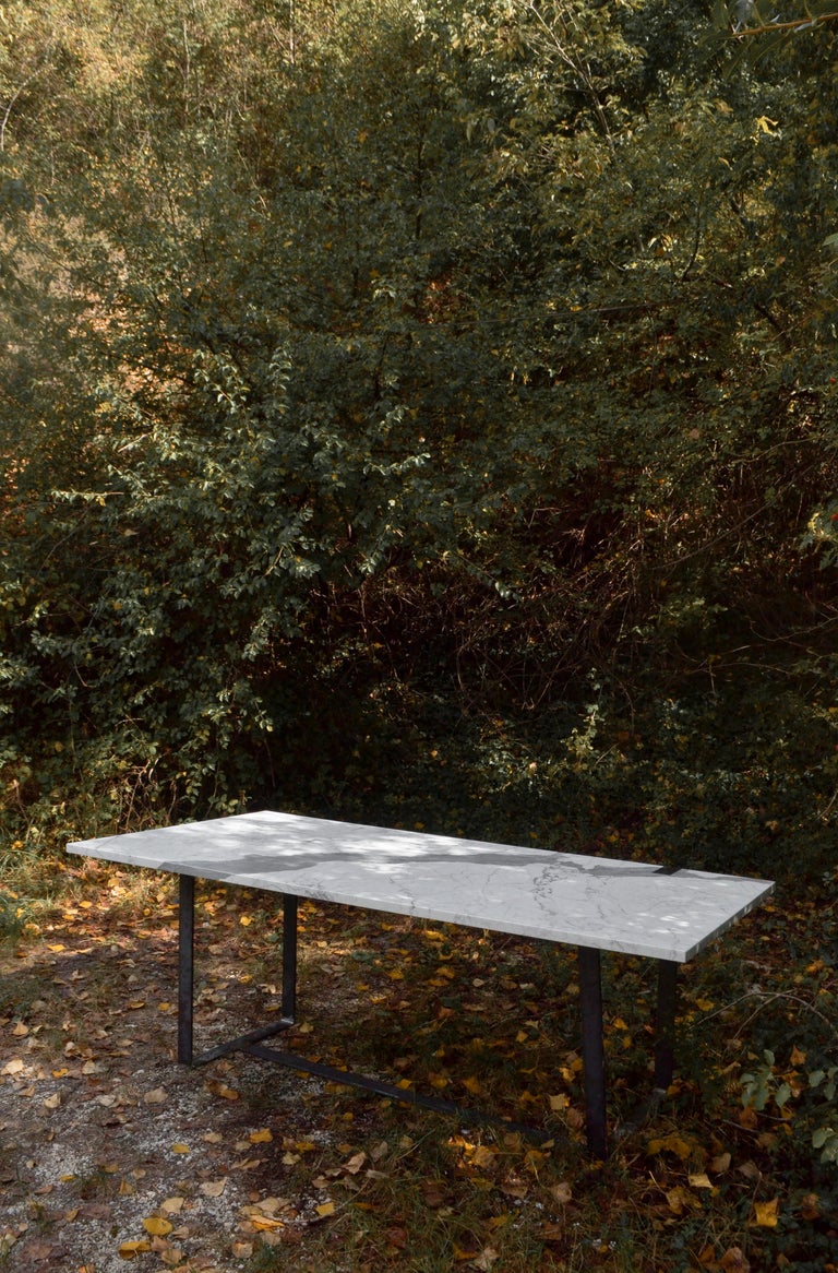 The trapezoidal top in Statuary marble with a natural and irregular texture is coupled with the linearity of the natural black iron legs. A material game that recalls the graft of trees present in nature.