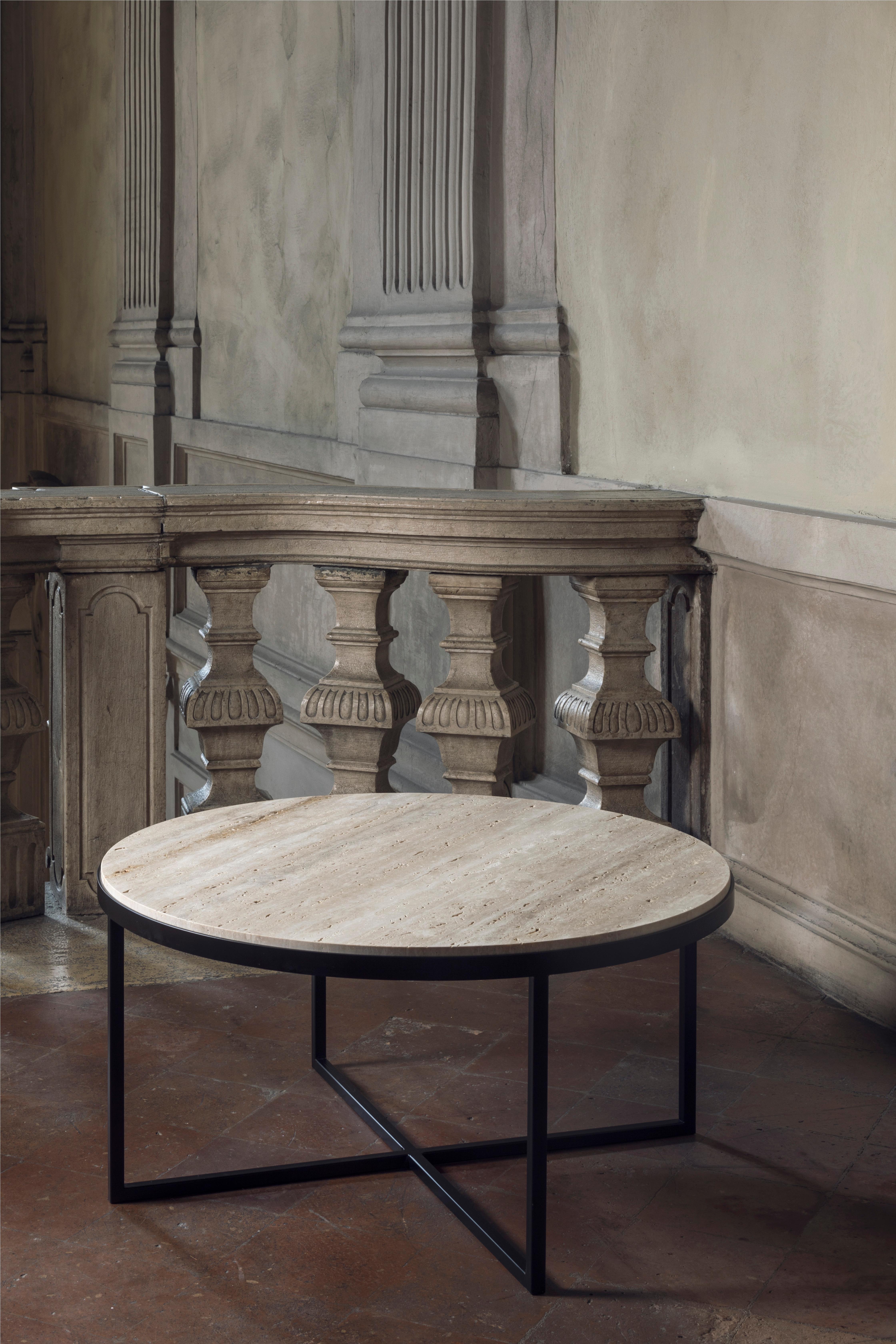 An essential perfection characterizes this coffee table, called Eclipse. The severity of the geometry of the structure, emphasized by the iron, is counterbalanced by the precious top in travertino, lying on the structure like a perfect round