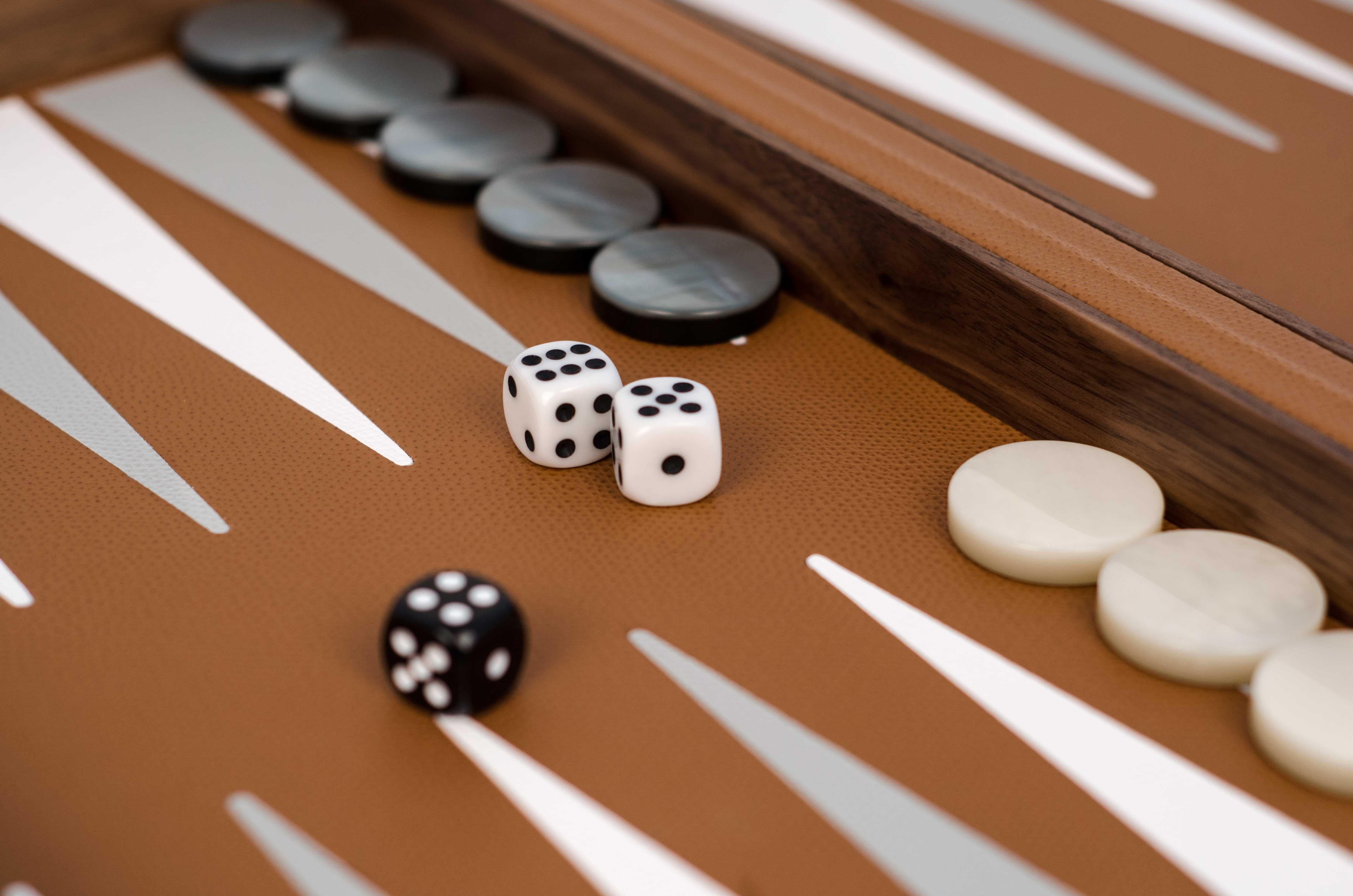 Our backgammon set, a must of board games.

Expertly crafted with canaletto walnut wood and dressed on the outside with a textured calfskin leather covering, its interior delivers a colourful twist into a cream background. We can't get enough of