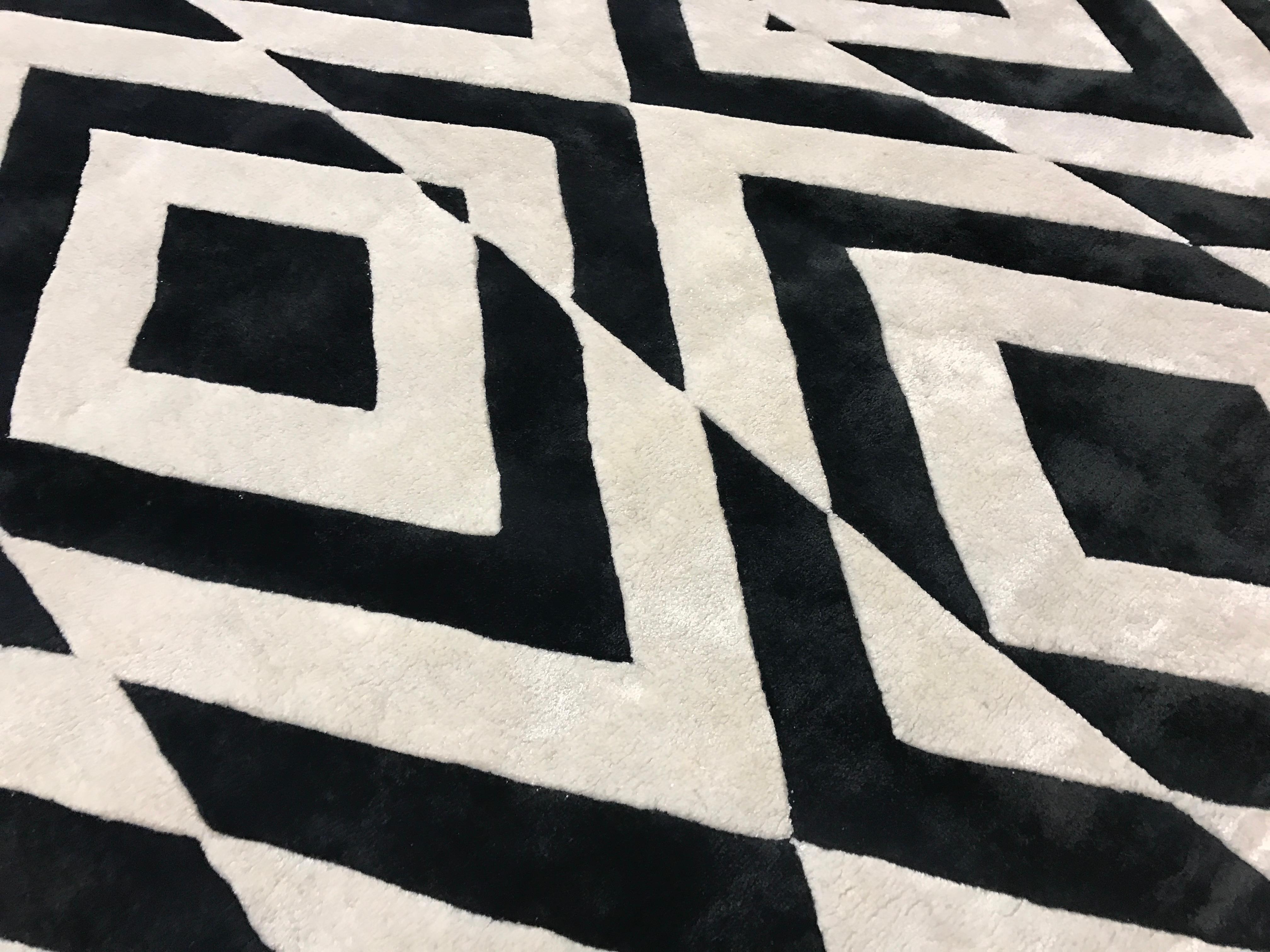 Die schwarze Seide der Dekoration bildet ein atemberaubendes Muster aus Rauten, die in versetzt angeordnete Streifen unterteilt sind.
Dieser Teppich wird in Nepal von unseren Kunsthandwerkern aus 50% Seide und 50% feiner Himalaya-Wolle handgeknüpft