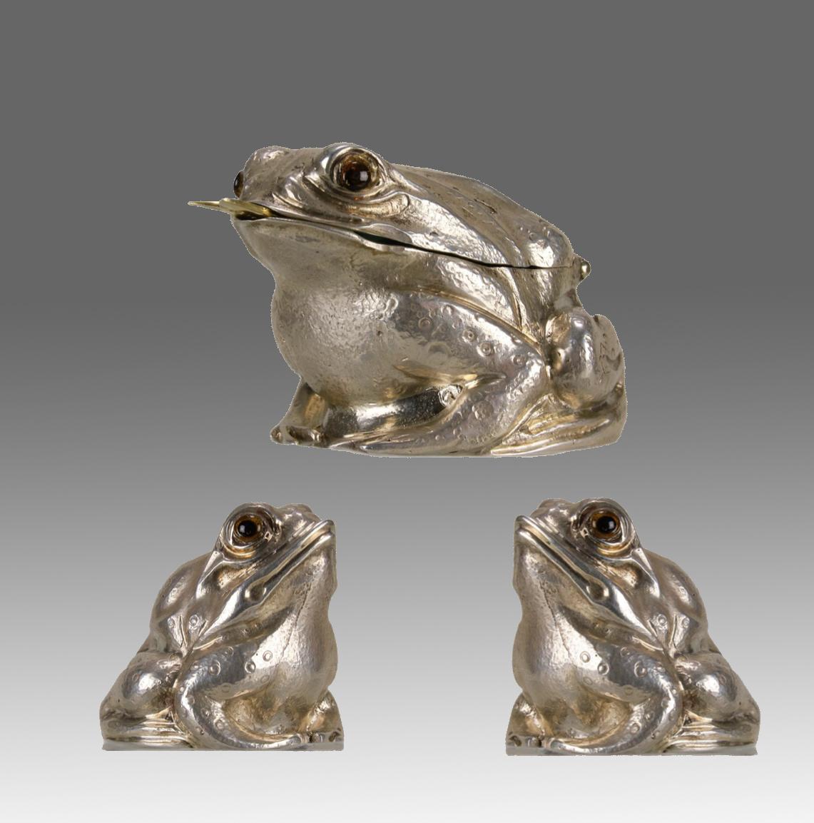 A charming solid silver cruet set modelled as three seated frogs. The set made up of a salt, pepper and mustard pot all with realistic garnet eyes. The mustard pot hinged at the frogs neck to reveal a green glass liner with silver gilt spoon