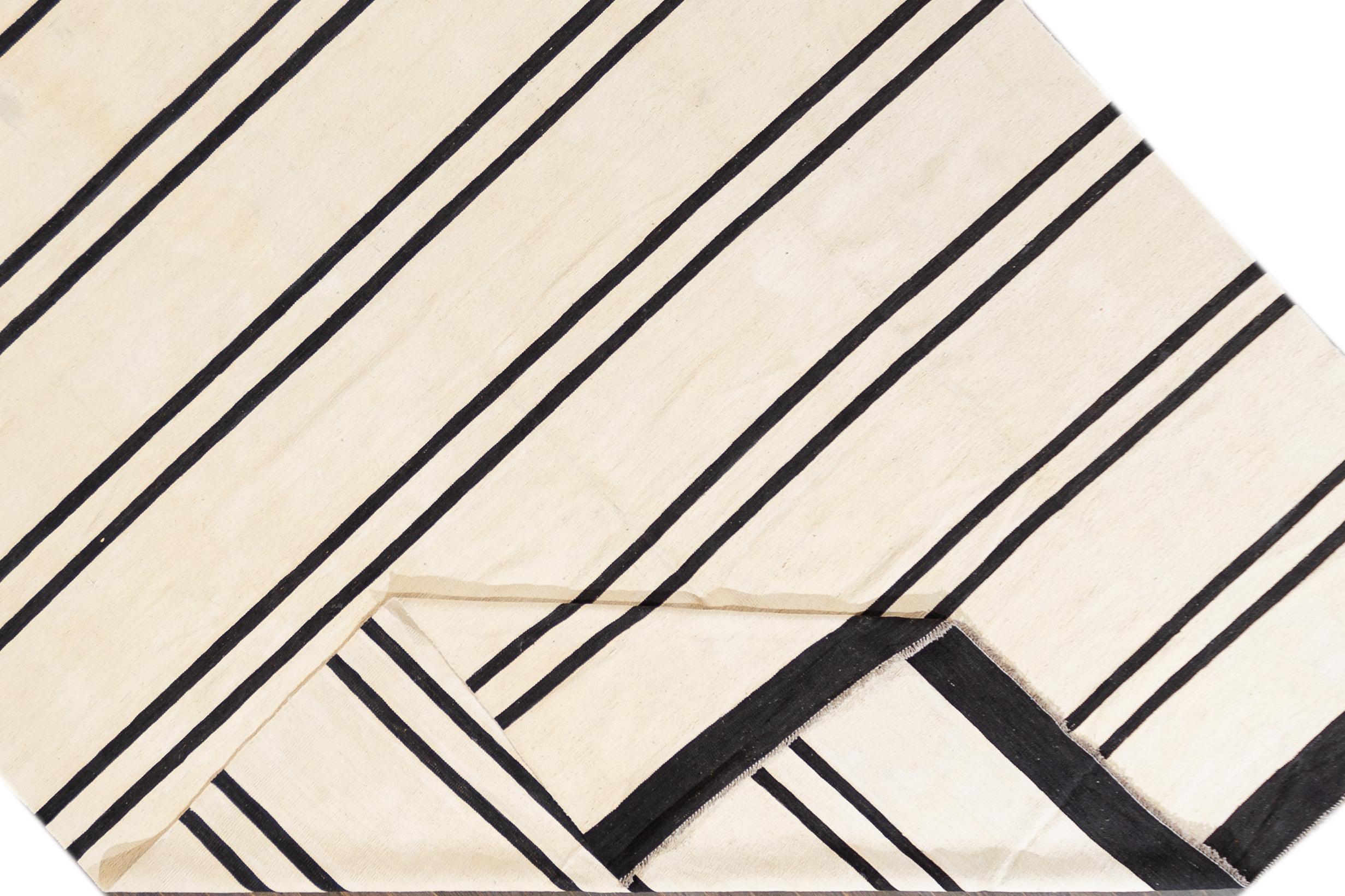 A contemporary black and white striped Kilim rug. This hand-woven flatweave wool rug measures 10'4