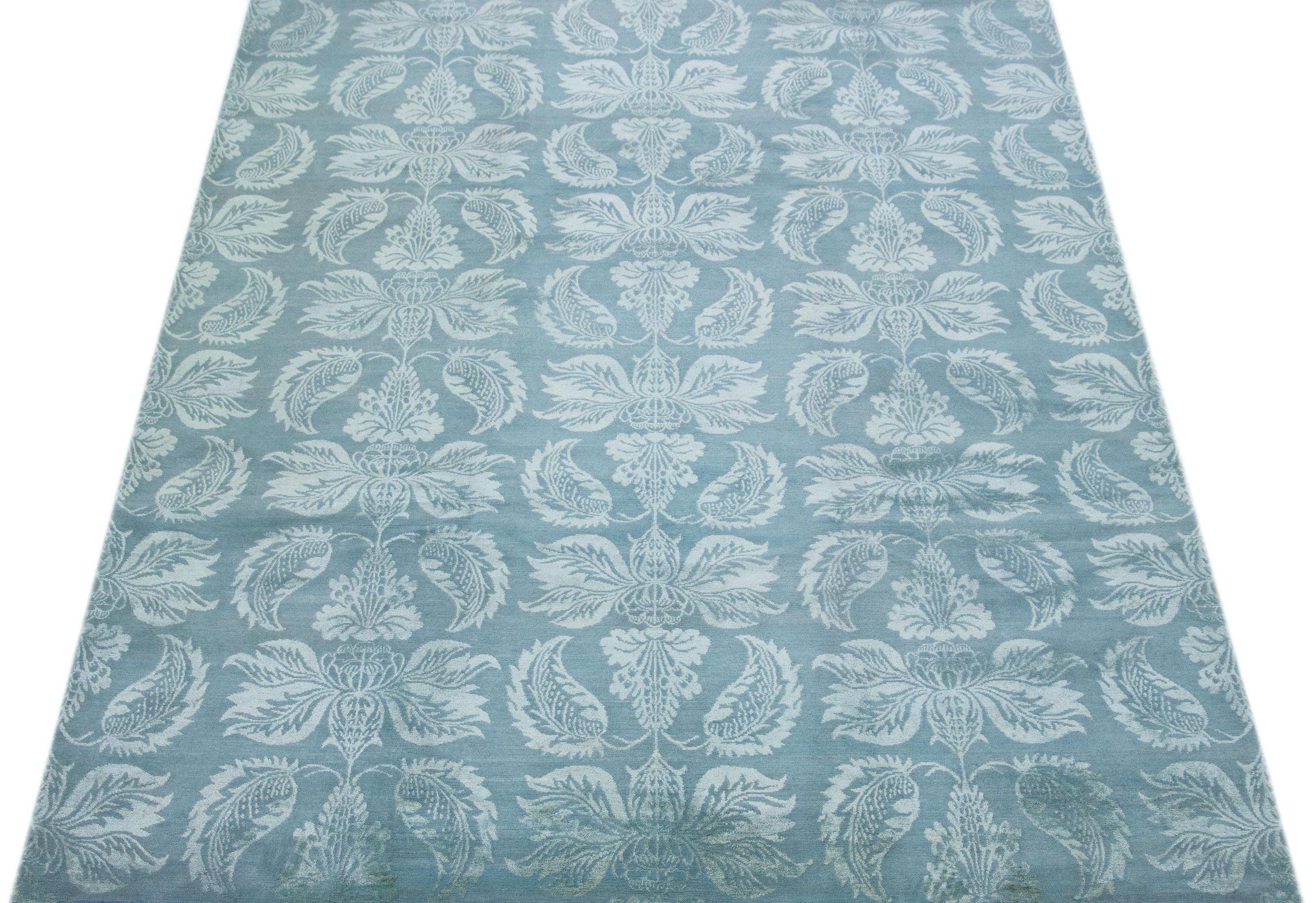 This contemporary Nepalese rug embraces a light blue floral motif that spans its all-over design. Its intricate details and striking color palette create a gorgeous piece. Consider adding this rug to your home decor for a touch of
