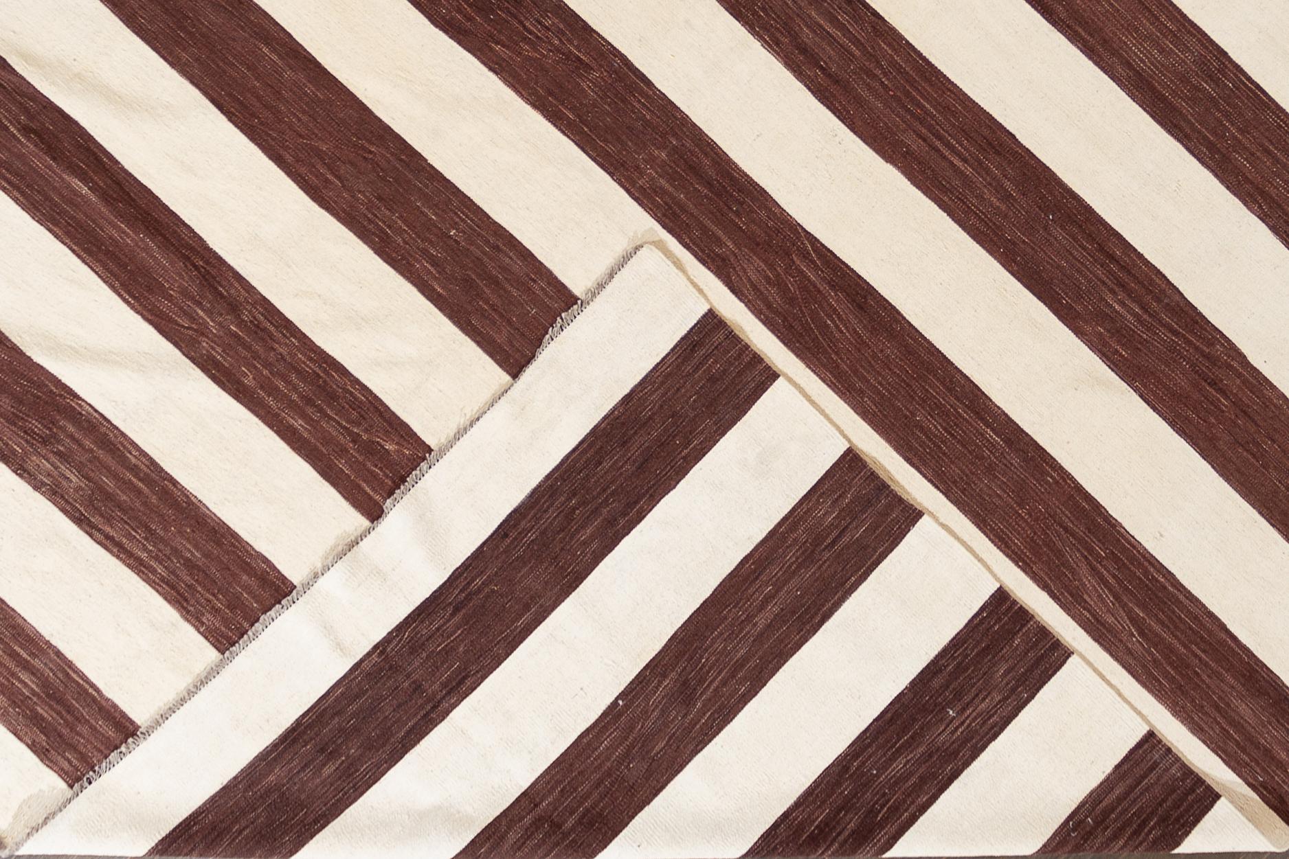 A contemporary brown and white striped Kilim rug. This hand-woven flatweave wool rug measures 12'0