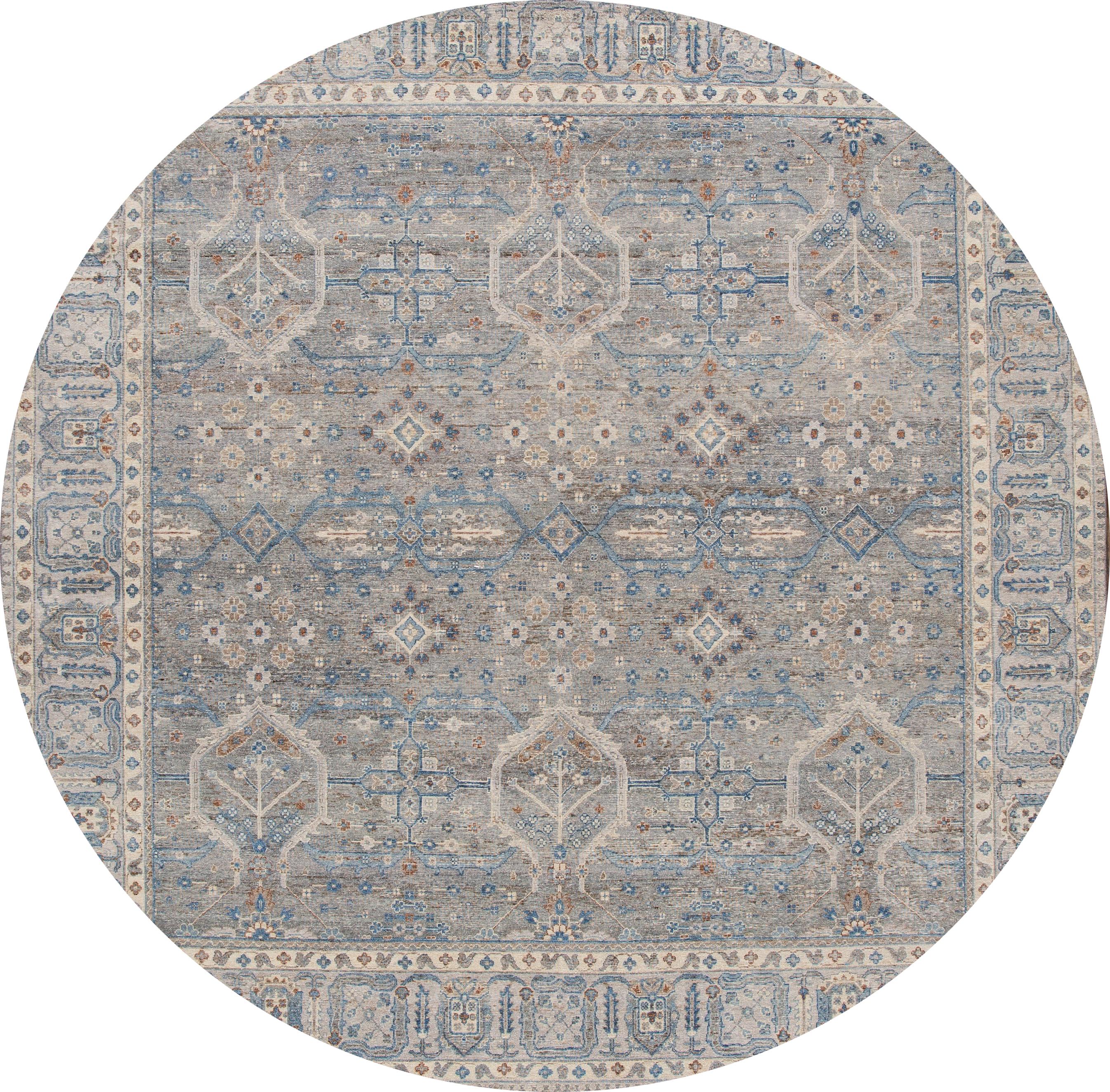 A contemporary square Tabriz-style rug with a gray field, and ivory and blue accents in asymmetrical, interconnected floral and vine design. This hand knotted Square wool.
This rug measures 10'1” x 10'4”.
