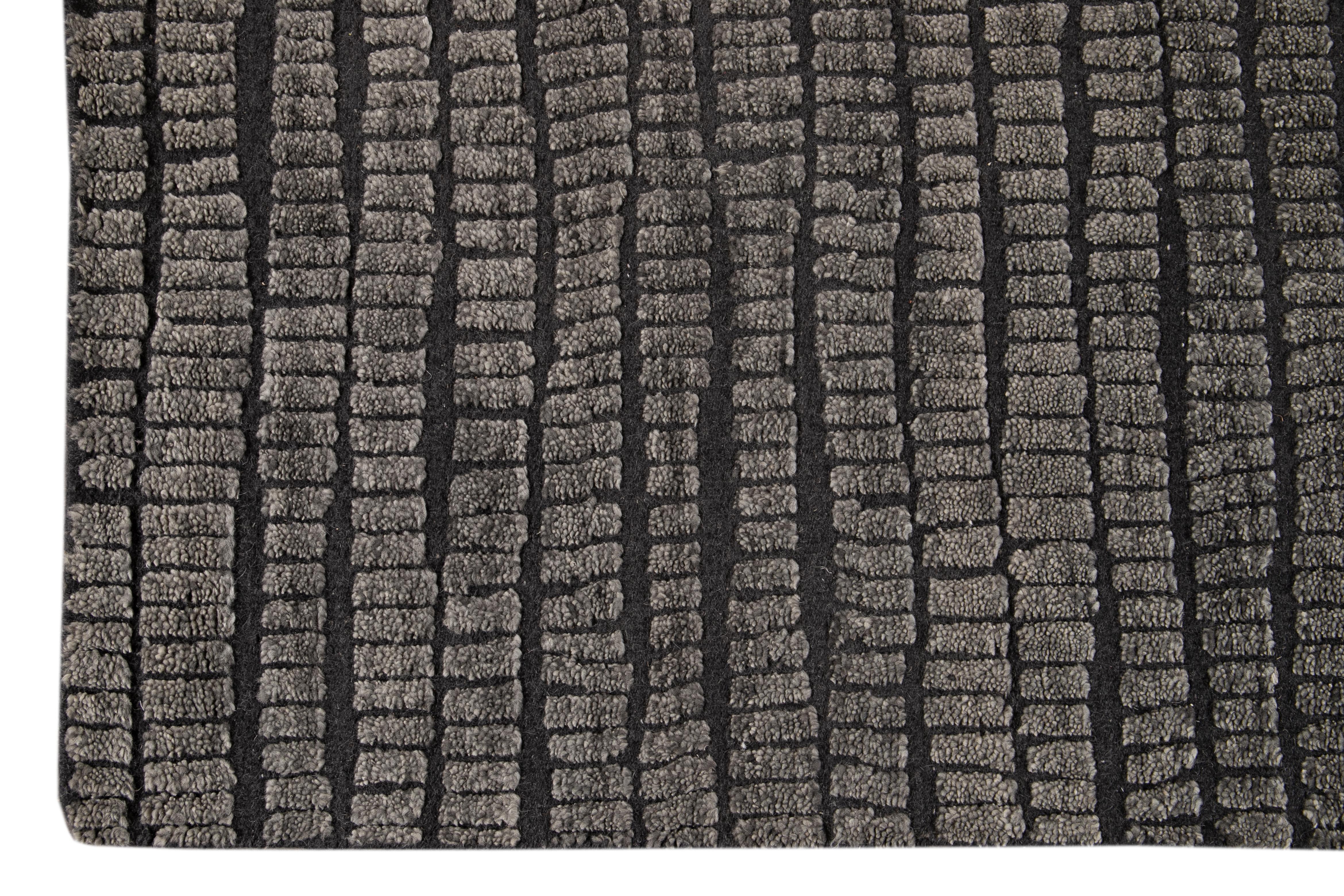 This contemporary textured Indian rug boasts a stunning high-low pile and all-over stripe pattern in a sophisticated dark gray hue.

This rug measures 9' x 12'.

circa 2019.