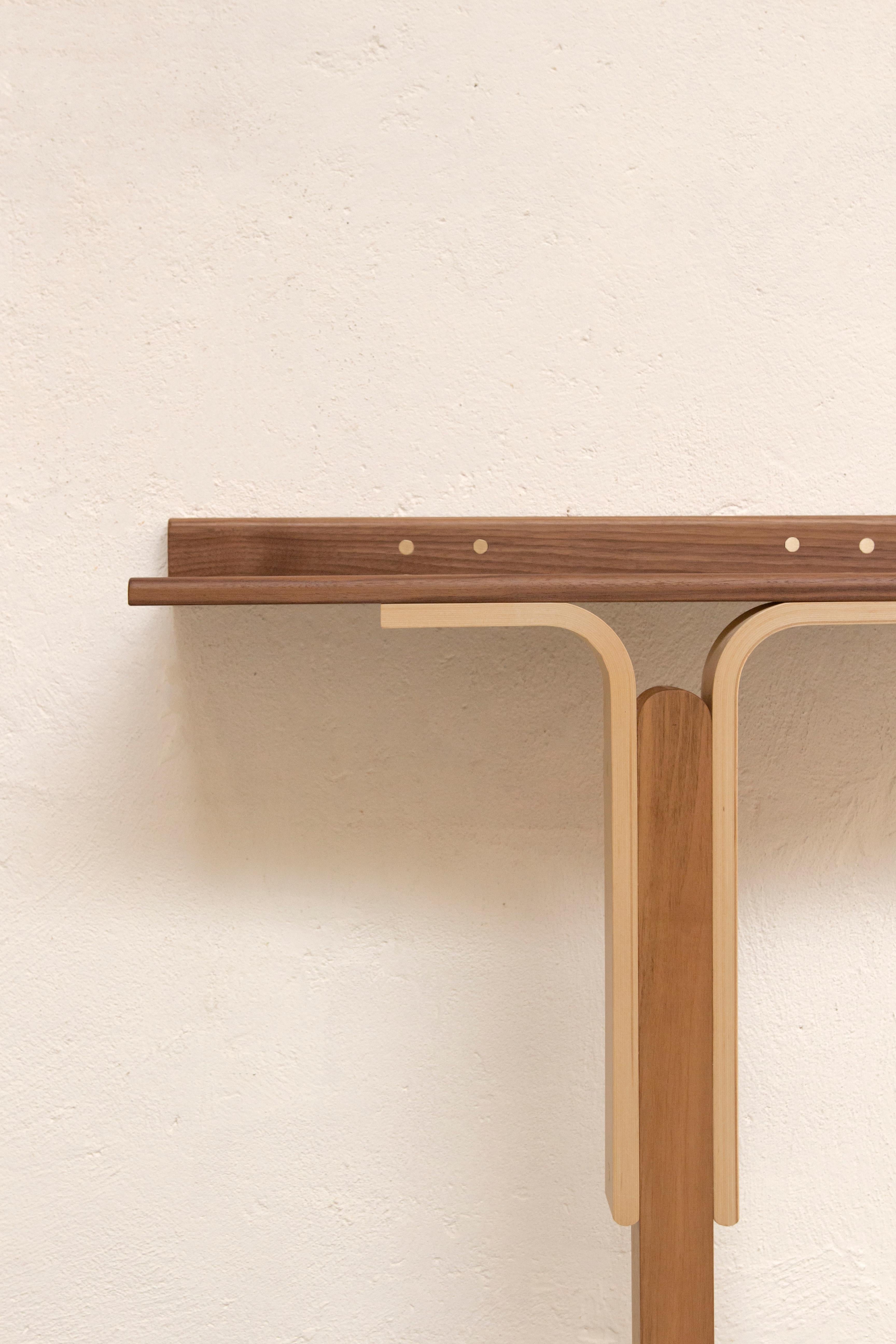 L'élégante table console Rennie d'Ilaria Bianchi, qui date du 21e siècle, est fabriquée à la main en bois massif de noyer et de frêne, avec une menuiserie en laiton poli. Les meubles sont agréablement sculptés dans une belle décoration en bois. La
