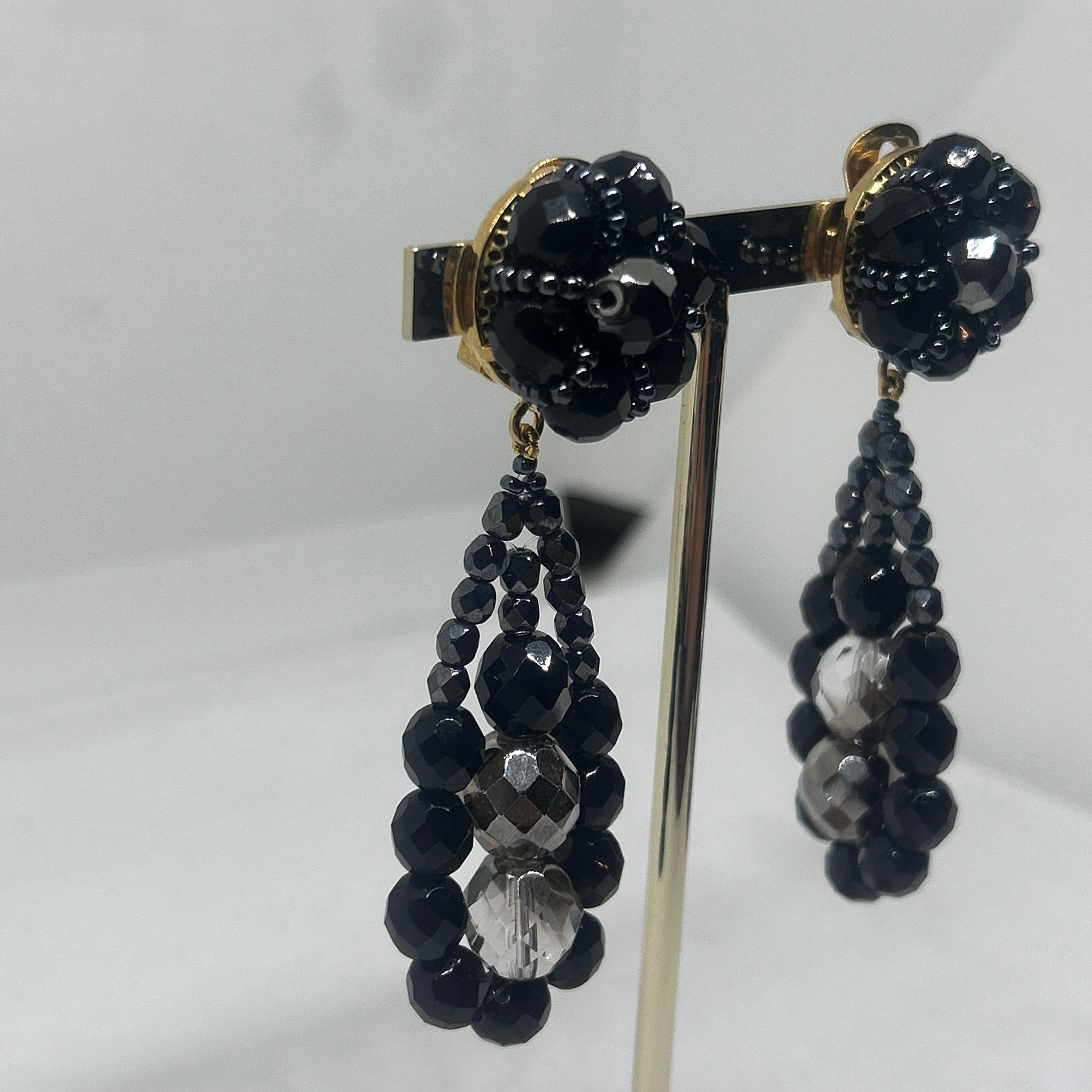 These earrings are bold and glamorous, characteristic of Coppola e Toppo’s intricate, luxury designs. 
Each earring features a **clustered floral-like top** composed of round, faceted black crystals that add texture and a subtle shine. The drop