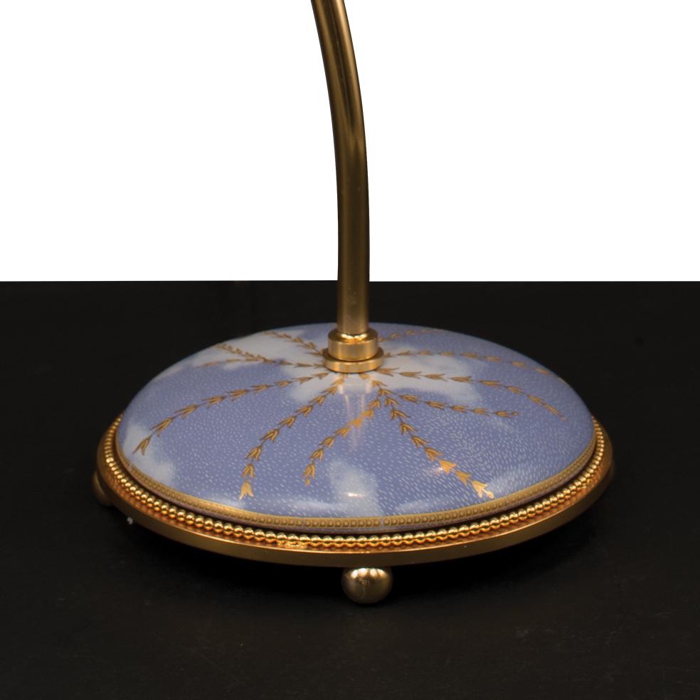 21st Century desk lamp in golden bronze and with porcelain base decorated with sky with clouds and pure gold decorations. The metal parts are finely chiselled. The joint on the bar allows you to direct the light so as to illuminate the desired part.