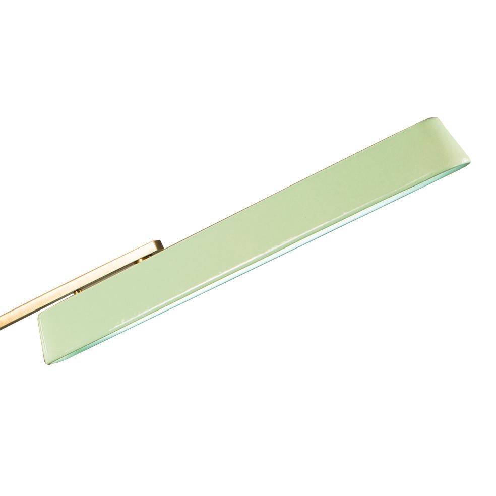 21st Century desk lamp in golden bronze and with green porcelain diffuser. The metal parts are simple and linear. The possibility of changing, on request, the metal finish and the color or decoration of the porcelain diffuser allows it to adapt to