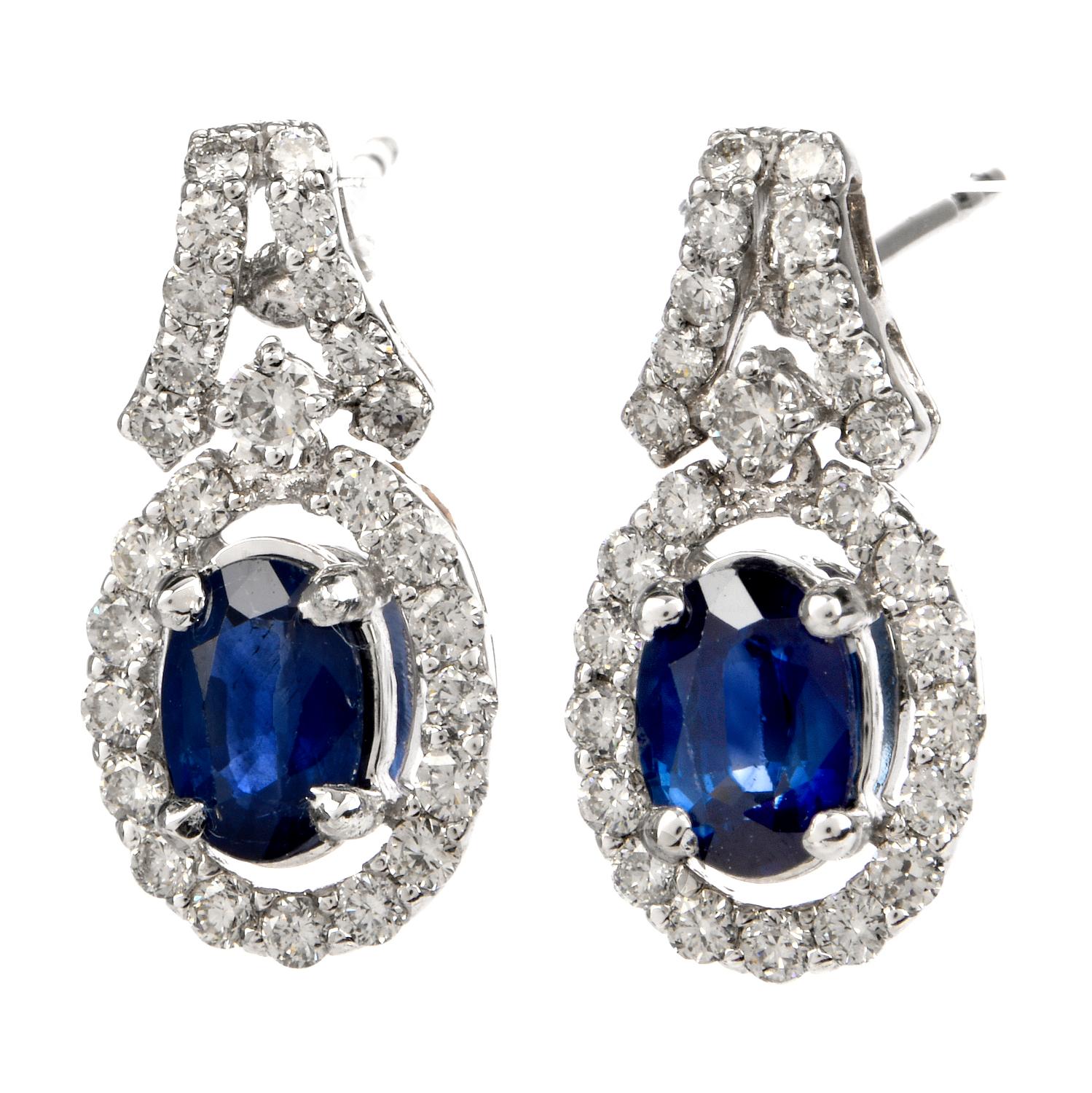 These shimmering diamond and blue sapphire drop earrings are crafted in 18-karat white gold, weighing 3.9 grams and measuring 17mm long x 9mm wide. Displaying a pair of prong-set oval shaped blue sapphires collectively weighing approximately, 0.95