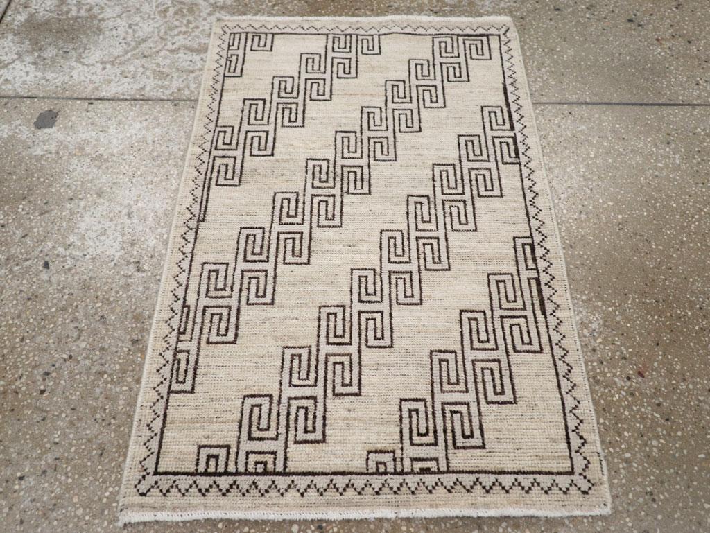 Un mucchio di lana con nodi asimmetrici su una base di cotone. Il campo di paglia sabbiosa ospita diagonali di traforo quadrato a spirale marrone, all'interno di un bordo a zig zag ecrù. Semplice ma grafico.

Misure: 1' 11