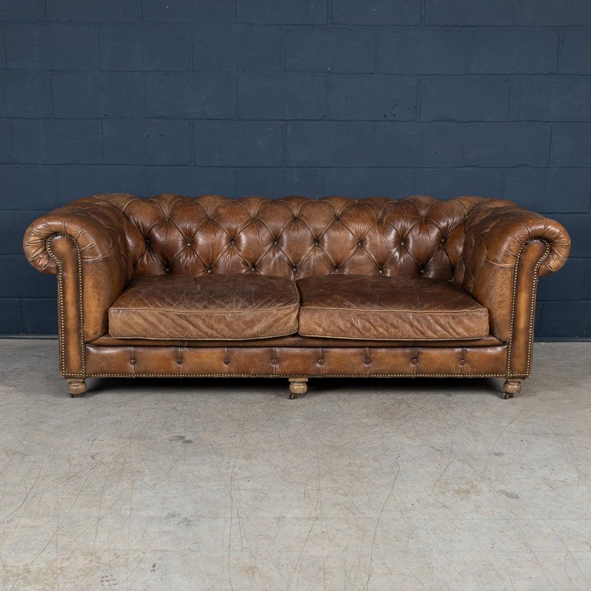 Un divano Chesterfield moderno di qualità superba che rappresenta una vera e propria dichiarazione di eleganza e maestria. Rifinita in ricca pelle marrone, presenta la classica imbottitura a bottoni, i braccioli arrotolati e la robusta struttura che