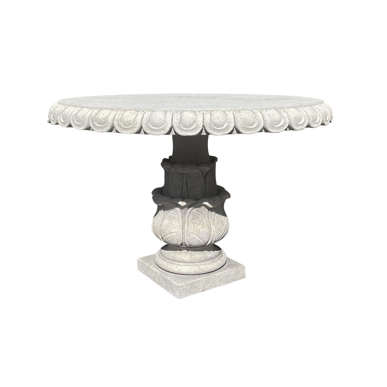 A circular limestone garden table with a 3.25” thick top and a decorative continuous egg and dart rim. Hand carved in limestone. The round baluster base is adorned by Acanthus leaves and is set on to a square base. Wear consistent with age and use.
