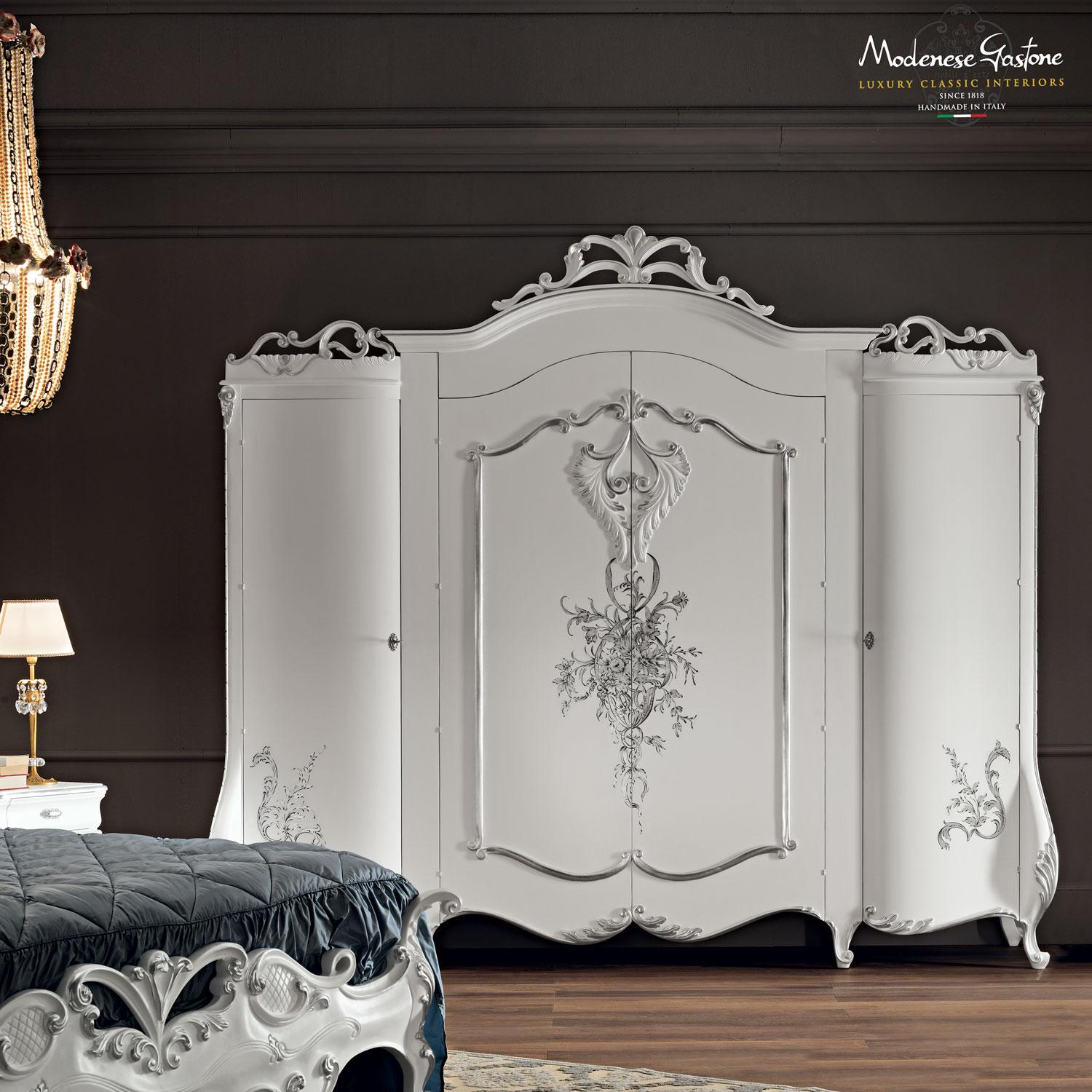 Gorgeous, handcarved baroque-inspired four doors white wardrobe by Italian producer Modenese Luxury Interiors. Features awe-inspiring handpainted floral decorations, and silver leaf applications on the carved ornamental elements. Best solution for
