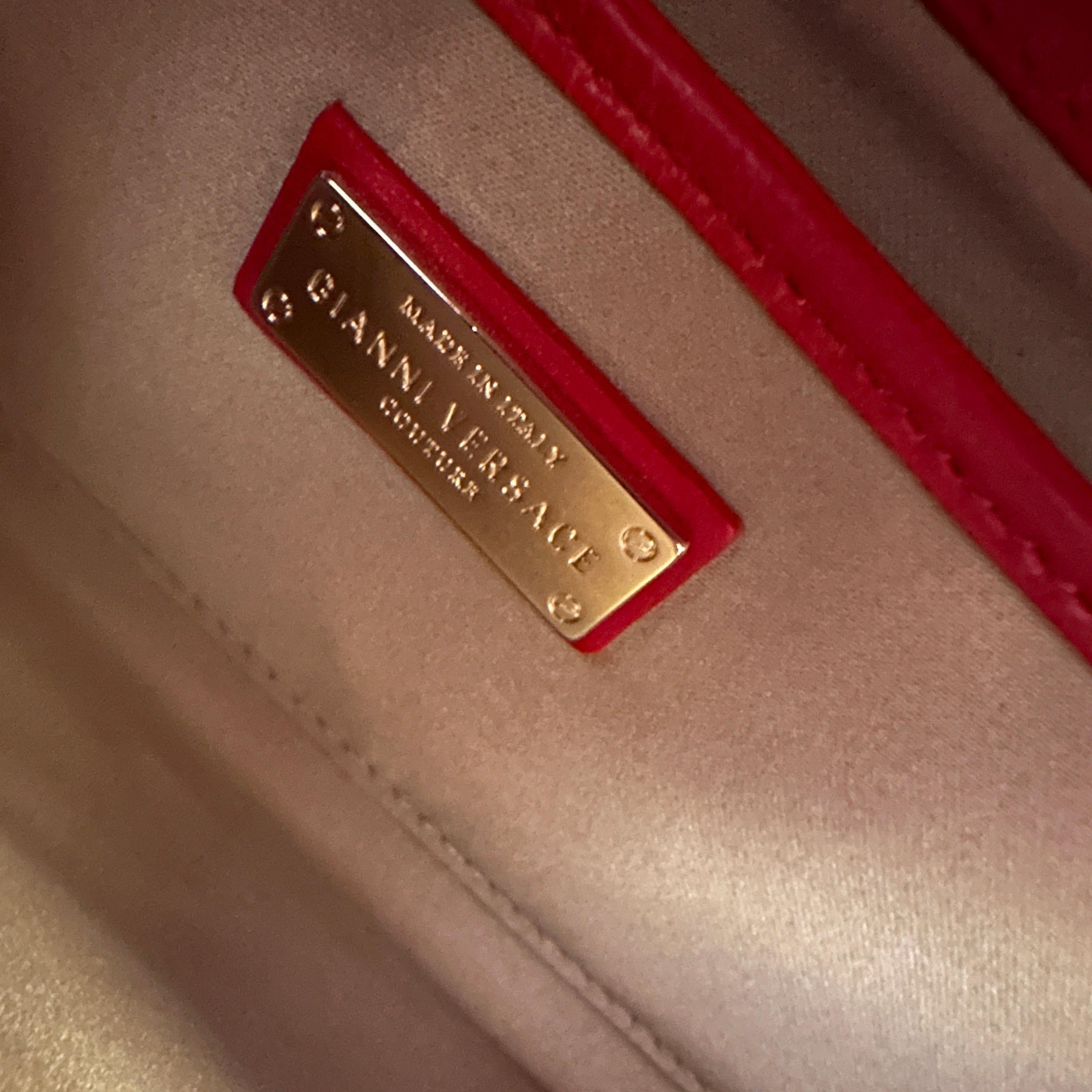 This exceptional shoulder bag by Gianni Versace is a true testament to 21st-century luxury and sophistication, merging timeless design elements with modern artistry. The bag's exterior is crafted from radiant red patent leather, which immediately