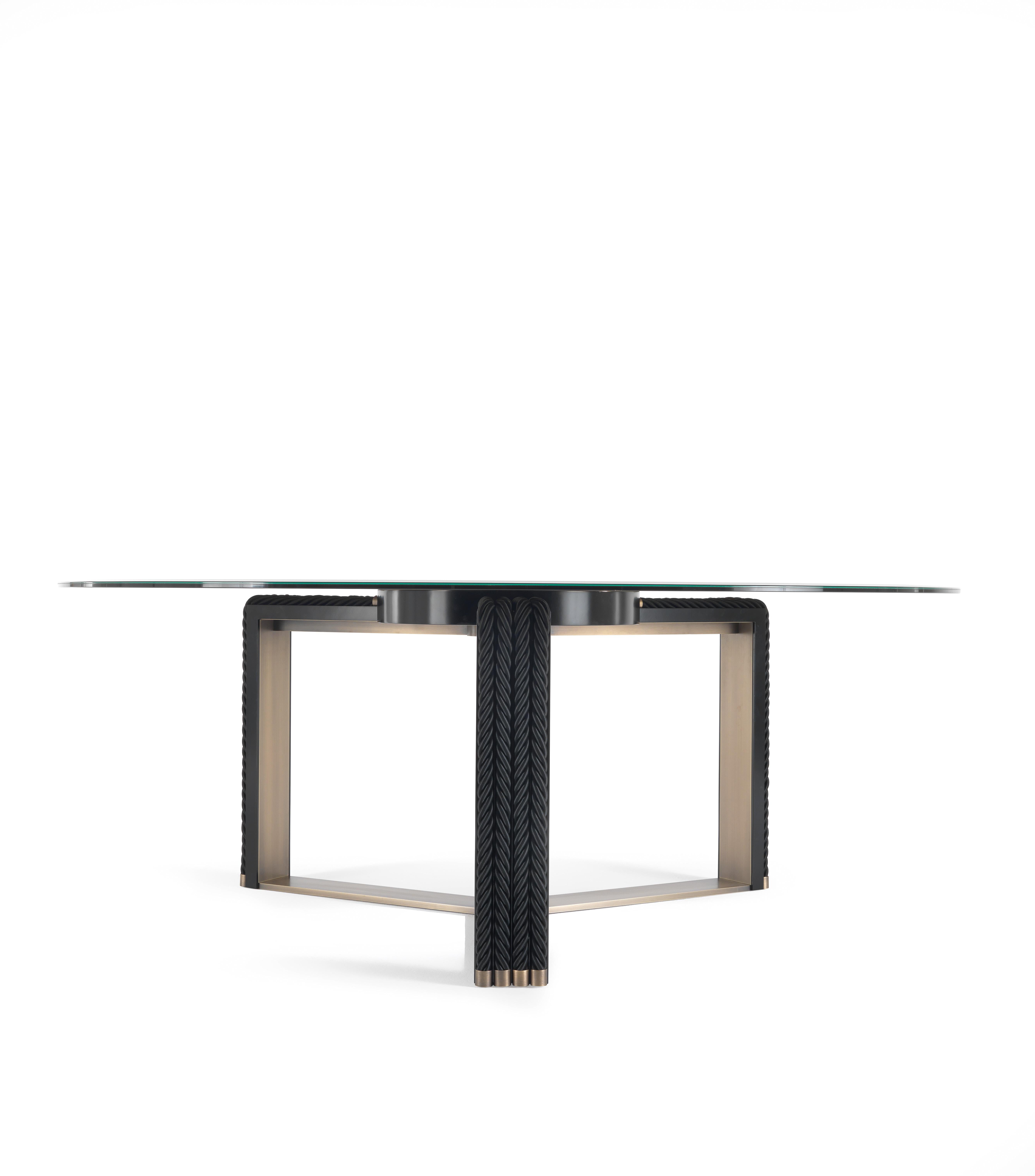 Protagonist of the dining room, the imposing Glasgow table has a coupled and ground bronzed glass top, anchored to a brass disc and equipped with a removable lazy susan. The unique base in bronzed brass consists of a single piece structured on three