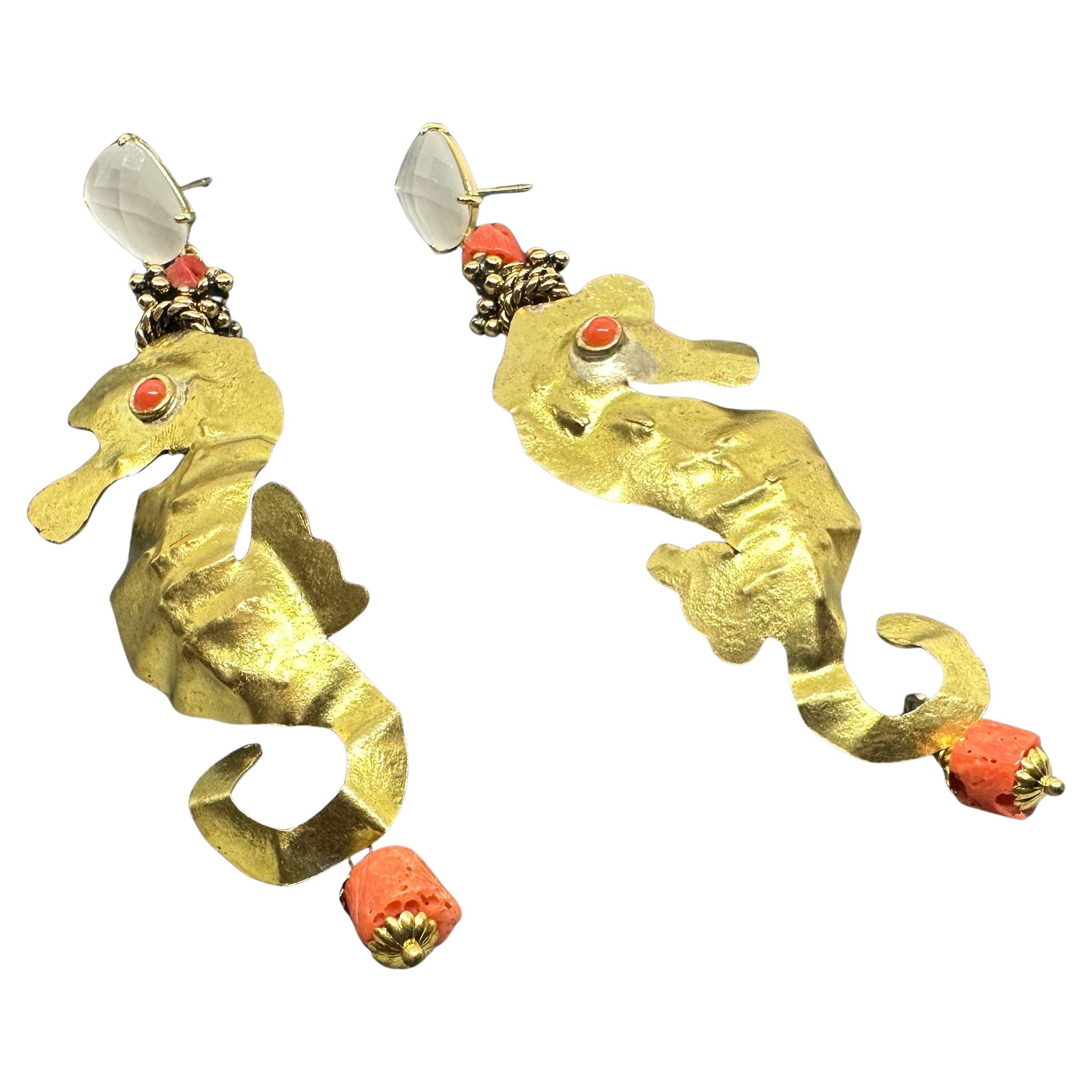 This pair of Italian earrings by Almala features a striking and whimsical design. They are shaped like seahorses, crafted from a gold-toned brass with a hammered finish that adds texture and depth. Each earring is embellished with mediterranean