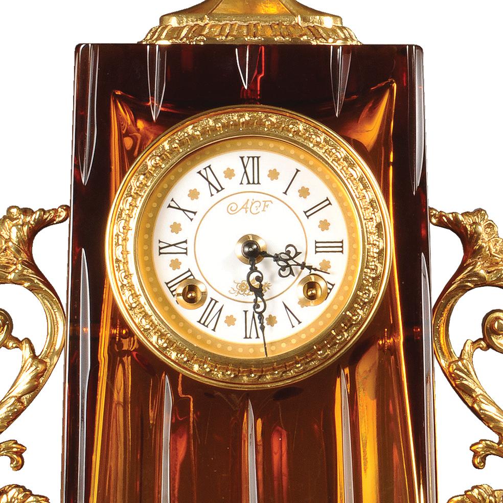 21st century Hand carved amber crystal and golden bronze clock. This clock is in hand-carved amber crystal and the dial is in white porcelain decorated in pure gold.  On request to customer can modificate the color of crystal: pink, clear, amethist