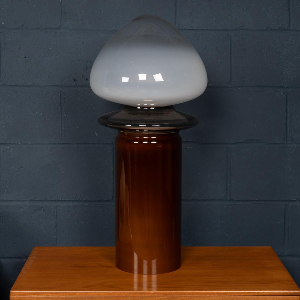 Cette lampe sculpturale en verre soufflé à la main, fabriquée à Murano, Venise, Italie, est un exemple étonnant de design contemporain. La lampe présente une composition superposée de trois éléments distincts : une base ambrée opalescente supportant