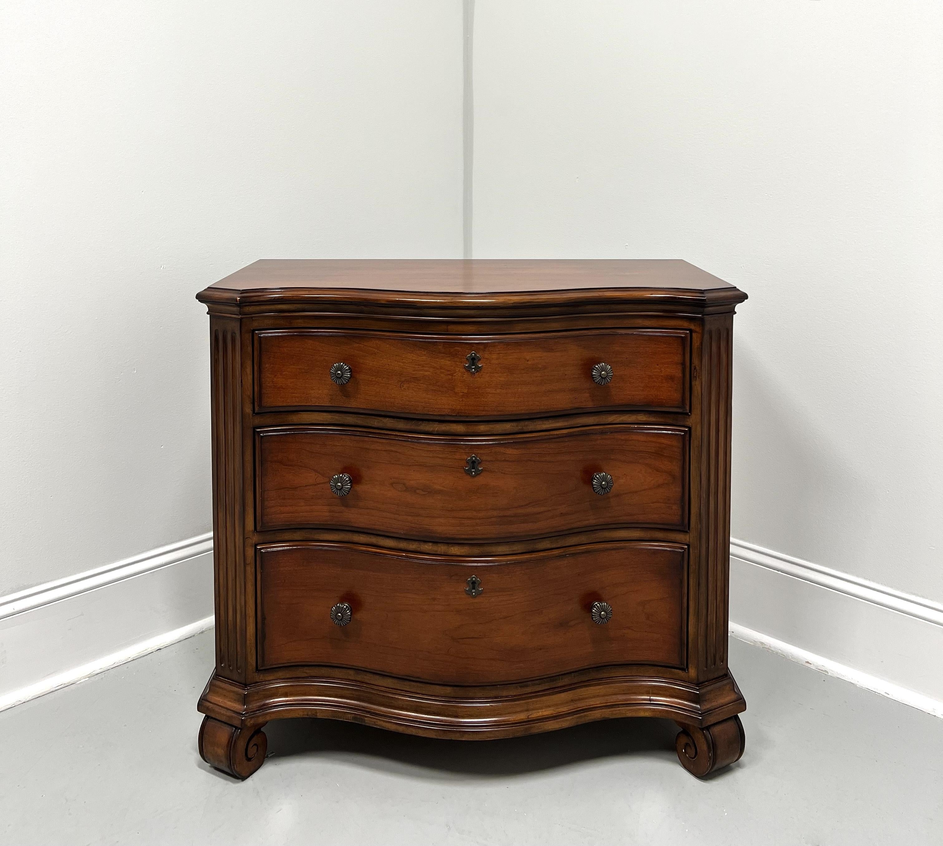 An Italian Tuscan style nightstand, unbranded. Cherry wood with decorative brass knob hardware, serpentine shape, ogee edge to the top with clipped front corners, fluted columns to front sides, faux keyhole escutcheons, and scroll feet. Features