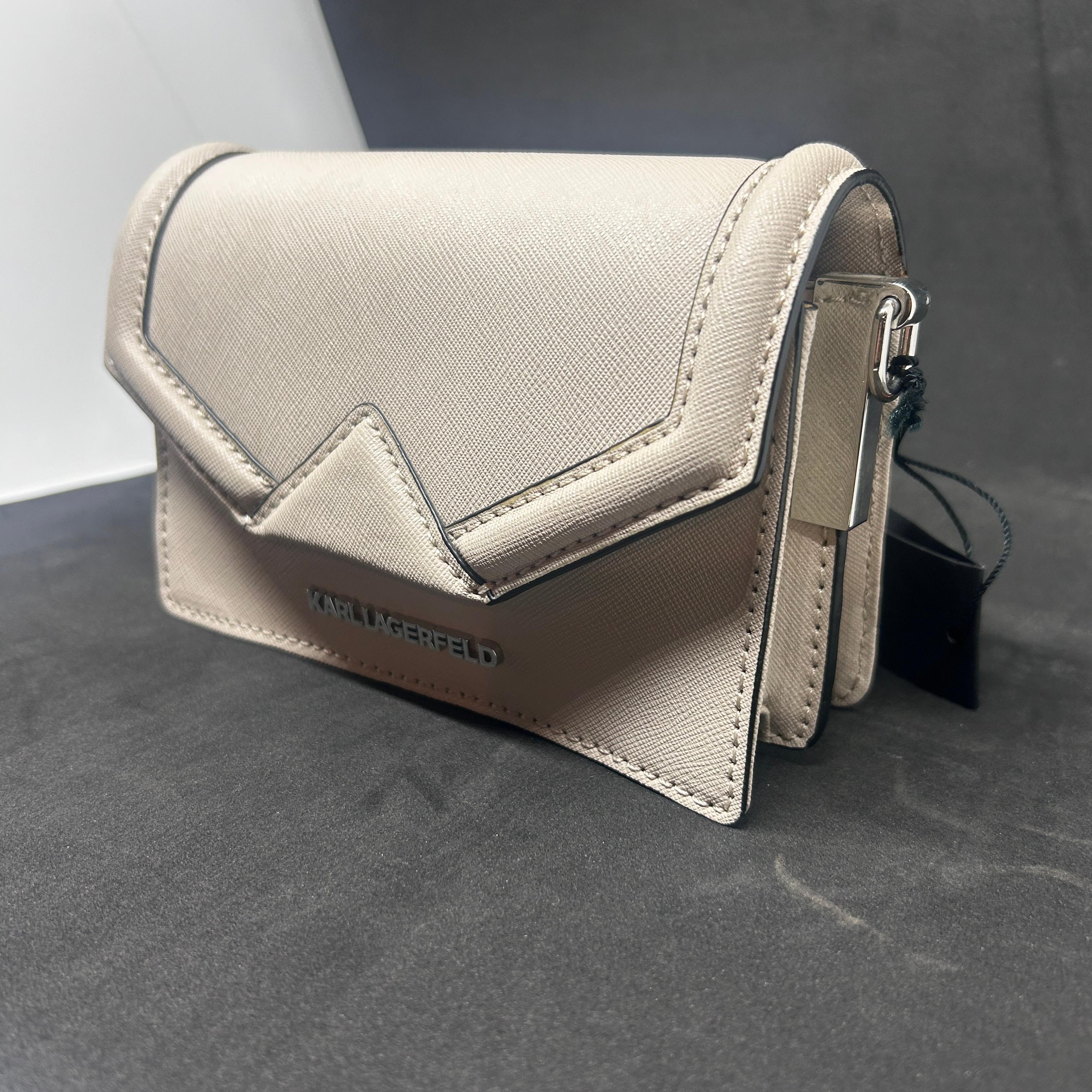 Questa mini pochette di Karl Lagerfeld del XXI secolo presenta un design elegante e moderno con una forma geometrica a busta. La borsa è disponibile in una sofisticata tonalità beige, che offre un tono neutro e versatile che si abbina bene a diversi