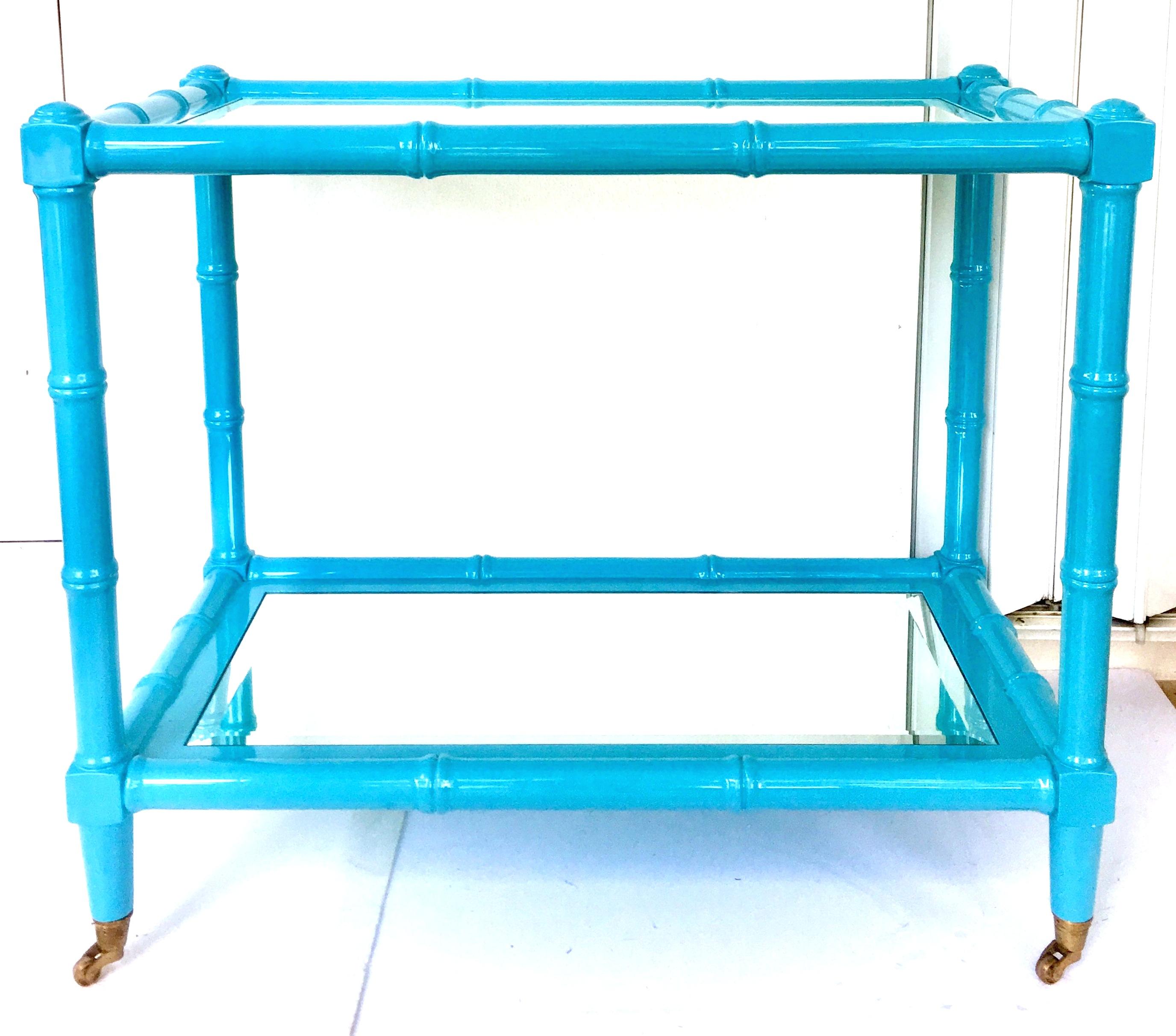 21st century lacquered wood faux bamboo and glass rolling bar cart. Features two beveled edge mirror tops, solid brass caster wheels and a high gloss vibrant turquoise lacquer finish.
Measures: Bottom shelf to top shelf distance, 22