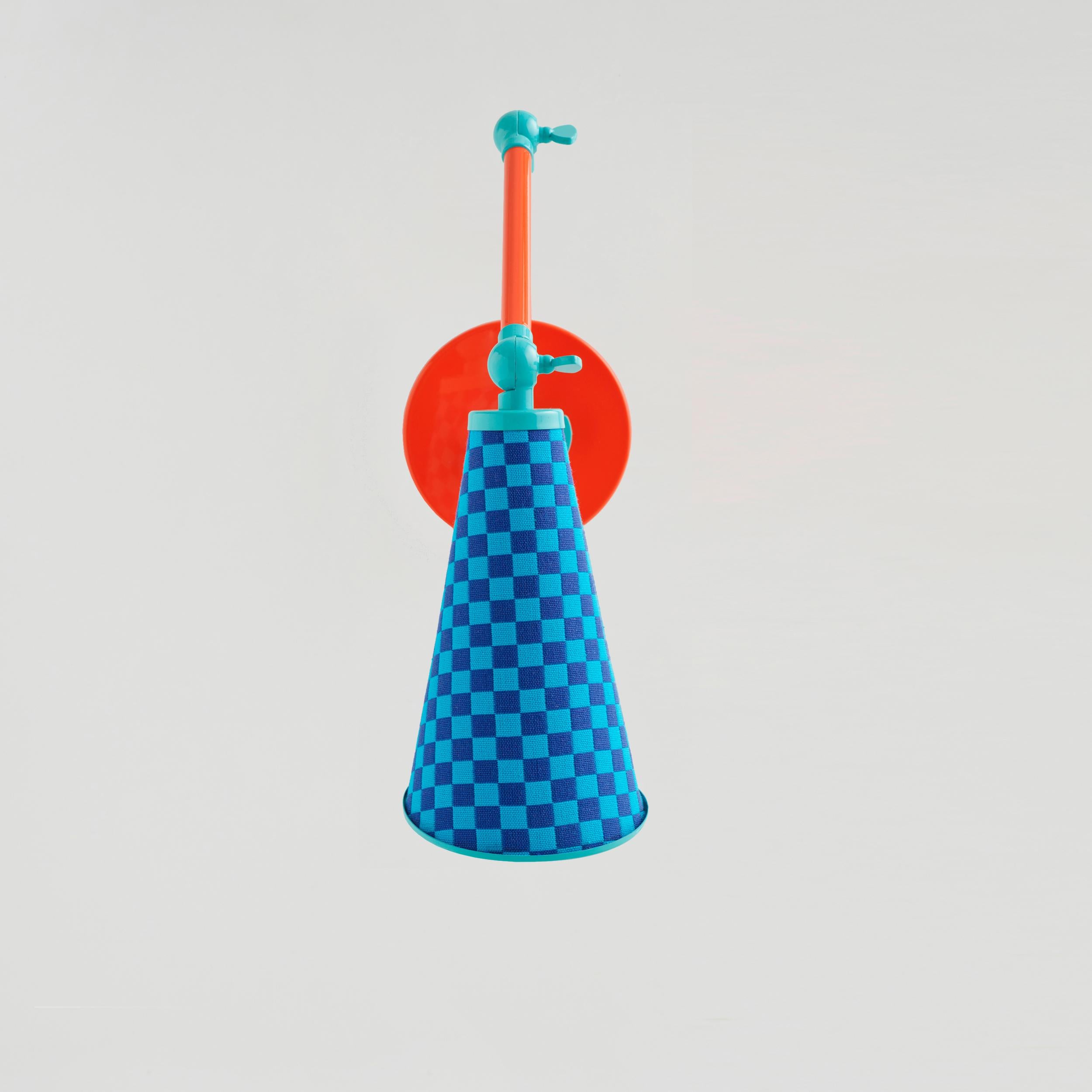 Lanterna sconce is a new age robot lamp with a heart. Unique Alexander Girard designed checkered fabric is combined with orange and light blue colored metal. Adjustable arms of Lanterna enables users to justify the form and position of the lamp.