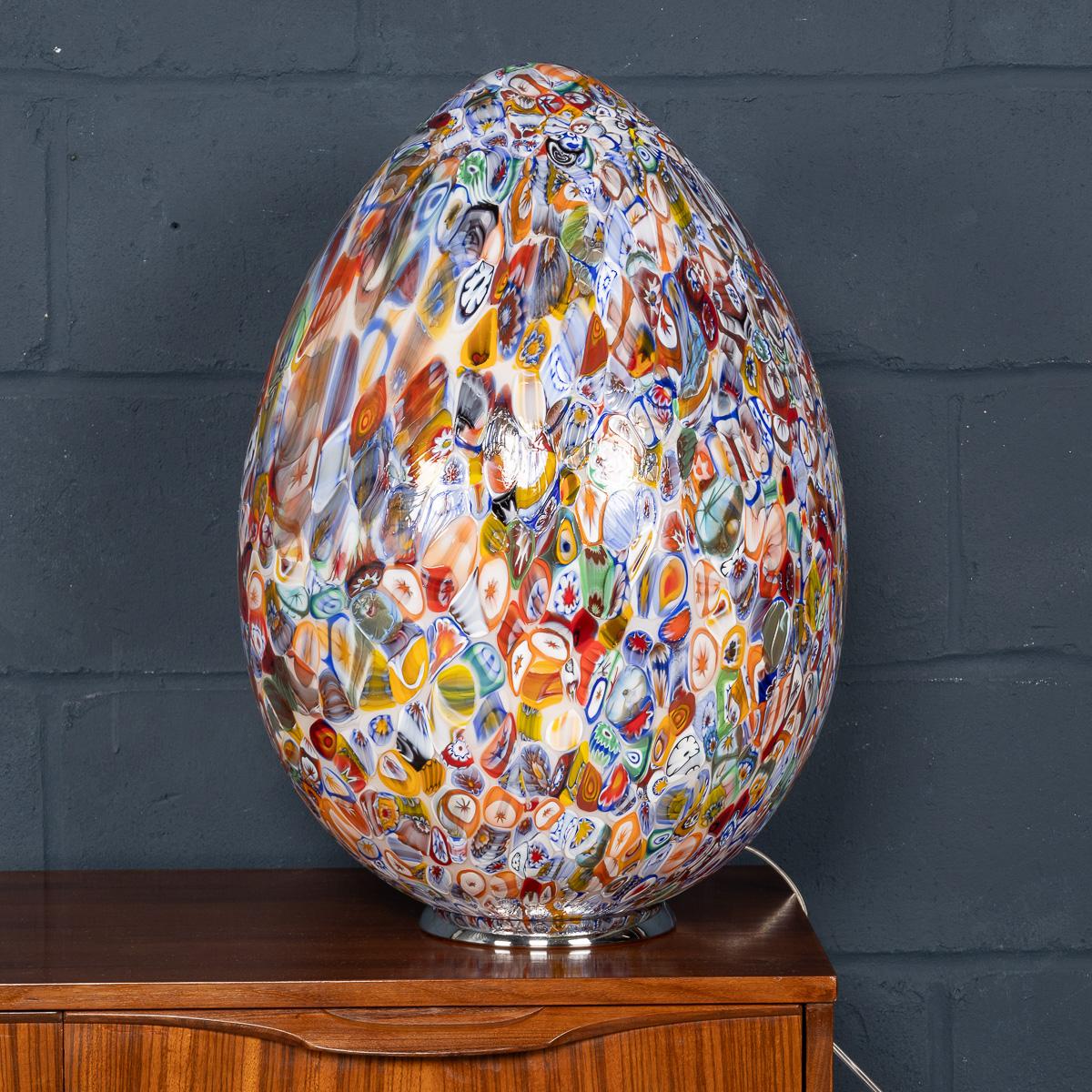 A large modern Murrina Millefiori table lamp, crafted in Murano, Venice, in Italy. It features an elegant, egg-shaped design that captures the essence of traditional Venetian glass artistry. The lamp’s surface is covered in intricate, multicoloured