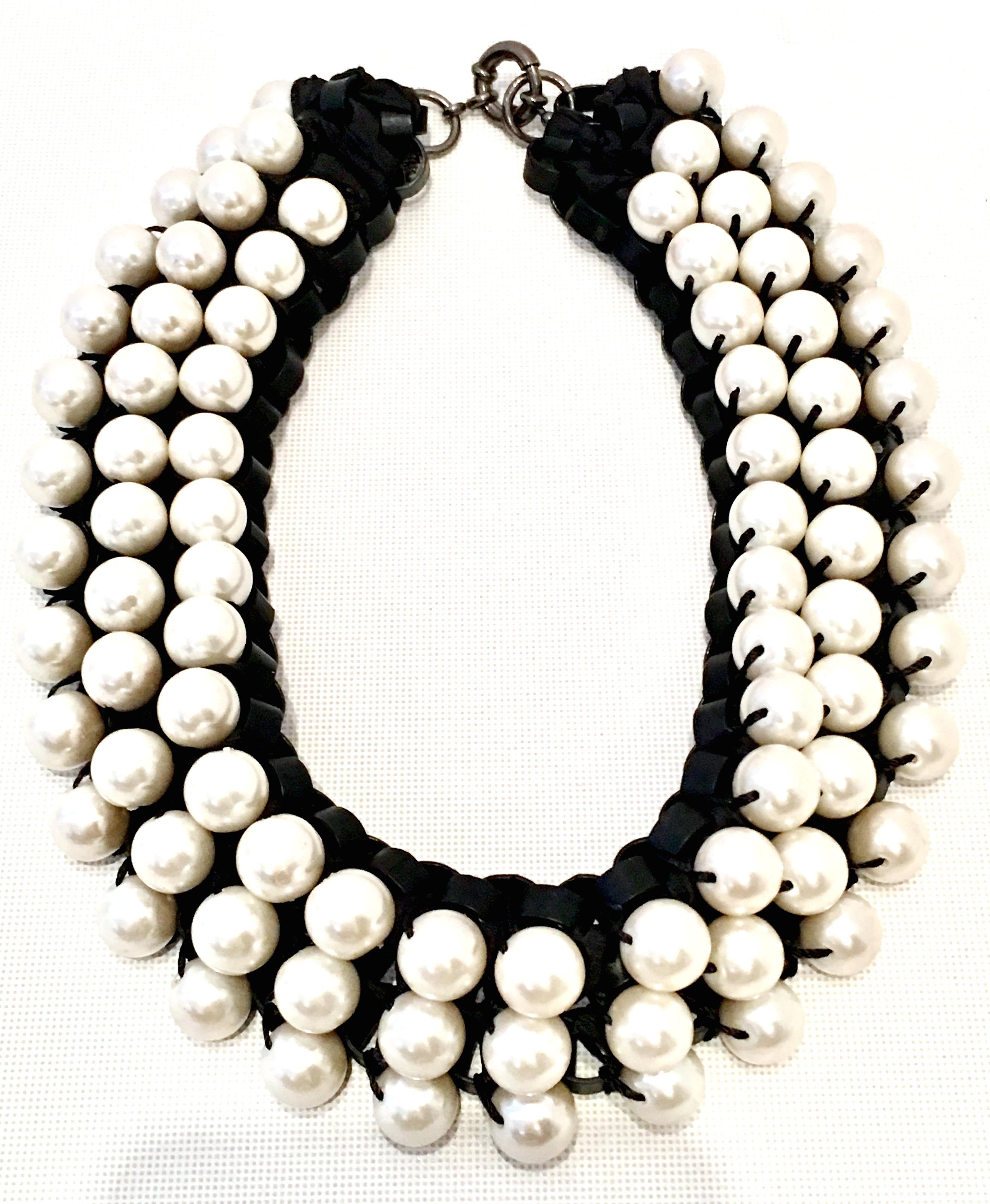 21st Century Leather & Faux Pearl Choker Style Necklace By, Lee Angel Martine. This chunky and substantial piece features woven black leather with a triple row of white faux pearls. The gunmetal tone metal locking claw clasp has a hang tag
