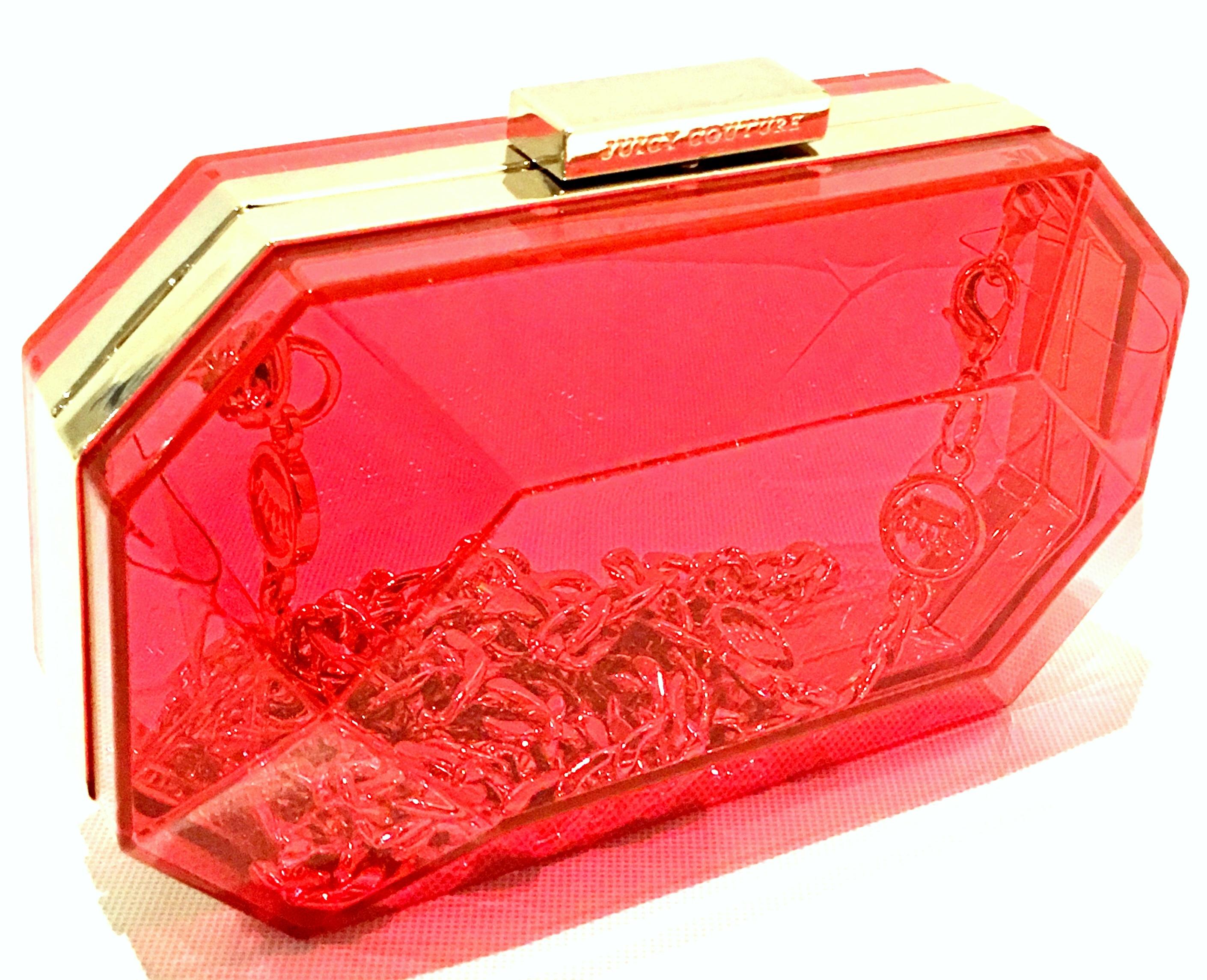 21st Century New Lucite & Gold Minaudiere Clutch Or Shoulder Bag By, Juicy Couture. Features a fuchsia to orange color with cut and faceted jewel shape. Gold bar snap closure with engraved Juicy Couture logo/font. Includes a 34