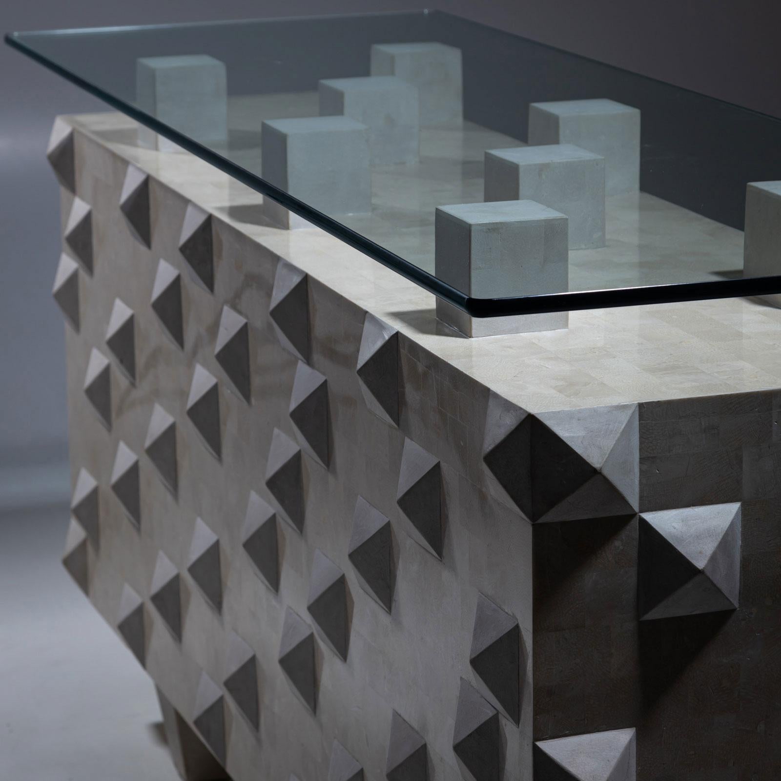 Ein bemerkenswerter Konsolentisch mit rechteckigem Sockel, der mit der Scagliola-Technik und warmem weißem Kalkstein gefertigt wurde. Die Oberfläche ist mit flachen Pyramiden verziert, die ein fesselndes Spiel von Licht und Schatten erzeugen. Der