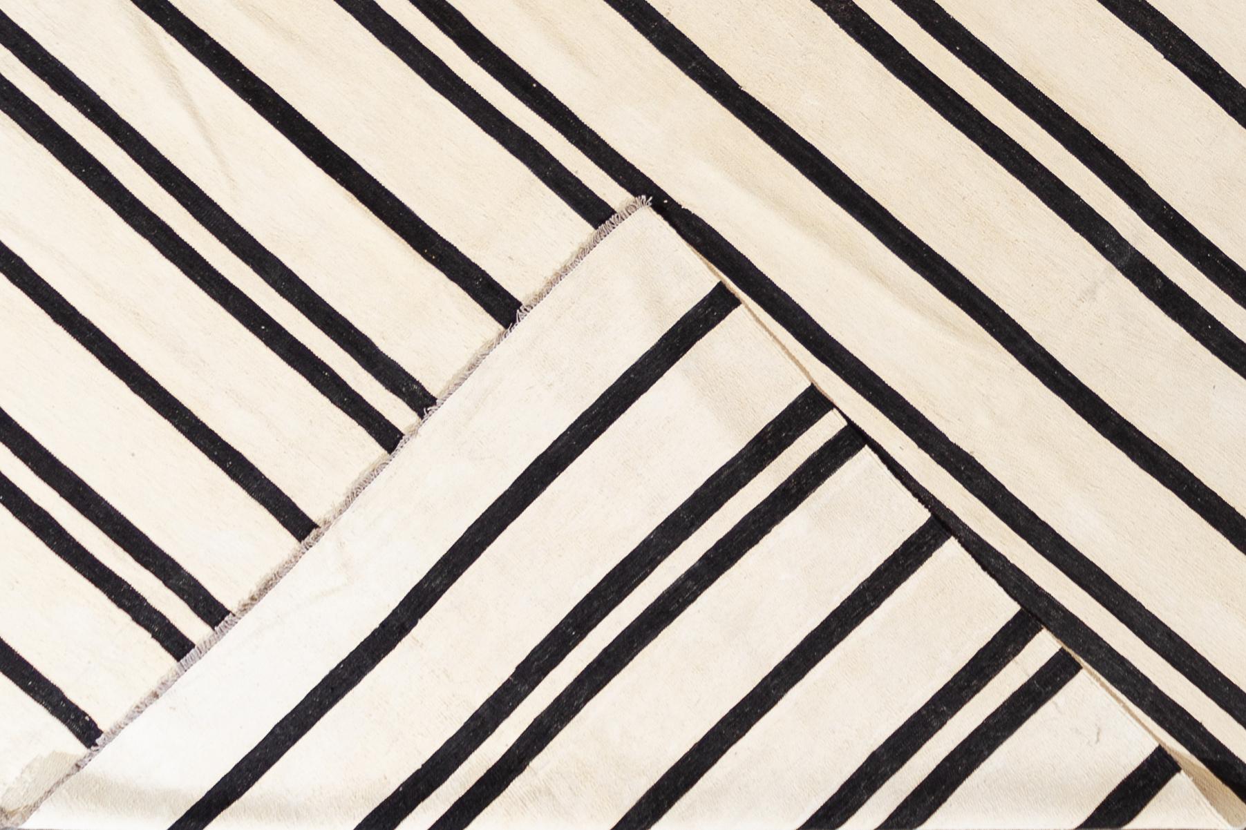 Beautiful 21st century contemporary Kilim Rug, handwoven wool in an all-over black and white striped design.
This rug measures 12' 1