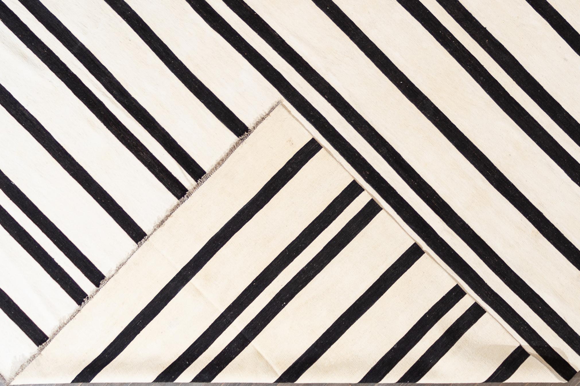 Beautiful 21st century contemporary Kilim rug, handwoven wool in an all-over black and white striped design.
This rug measures 12' 0