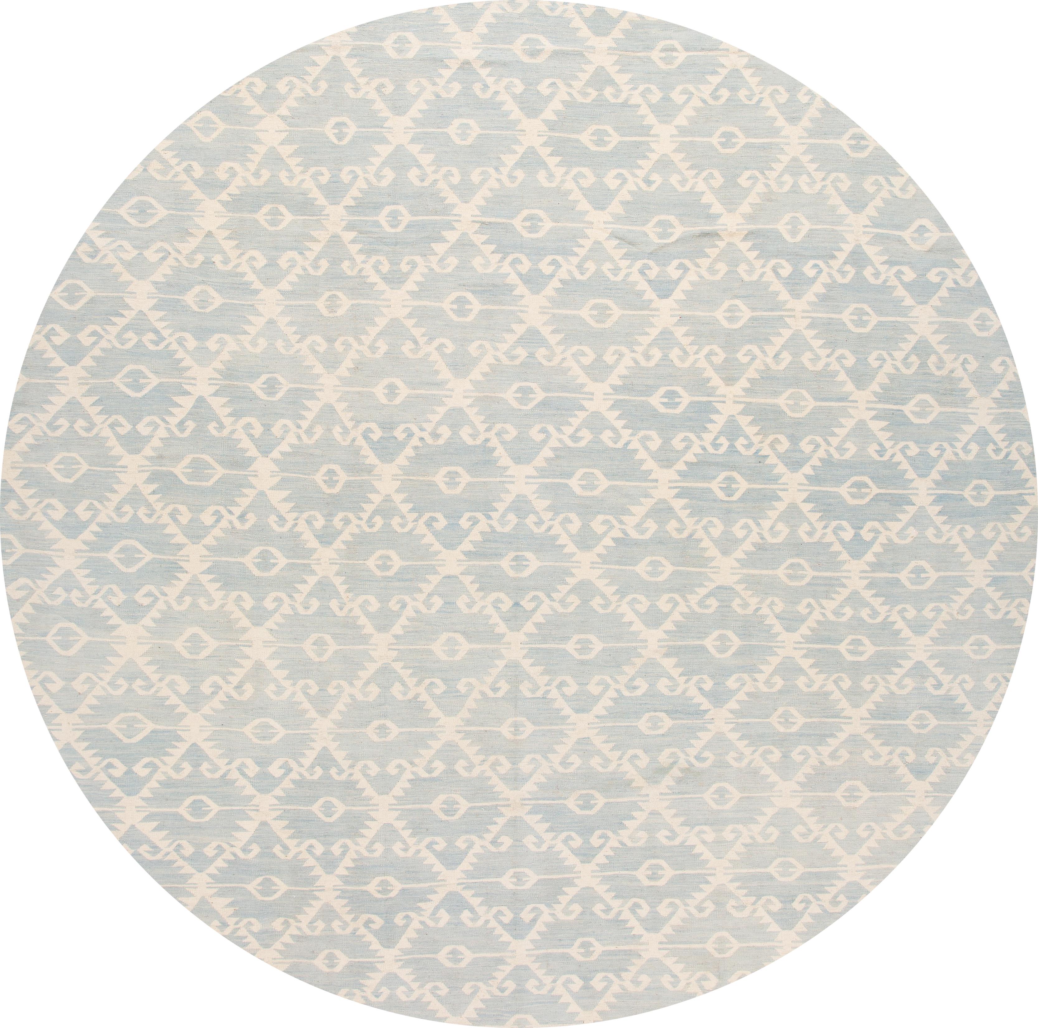 Beautiful 21st century contemporary Kilim handwoven wool rug with an ivory field in an all-over and blue diamond geometric design.

This rug measures 12' 9