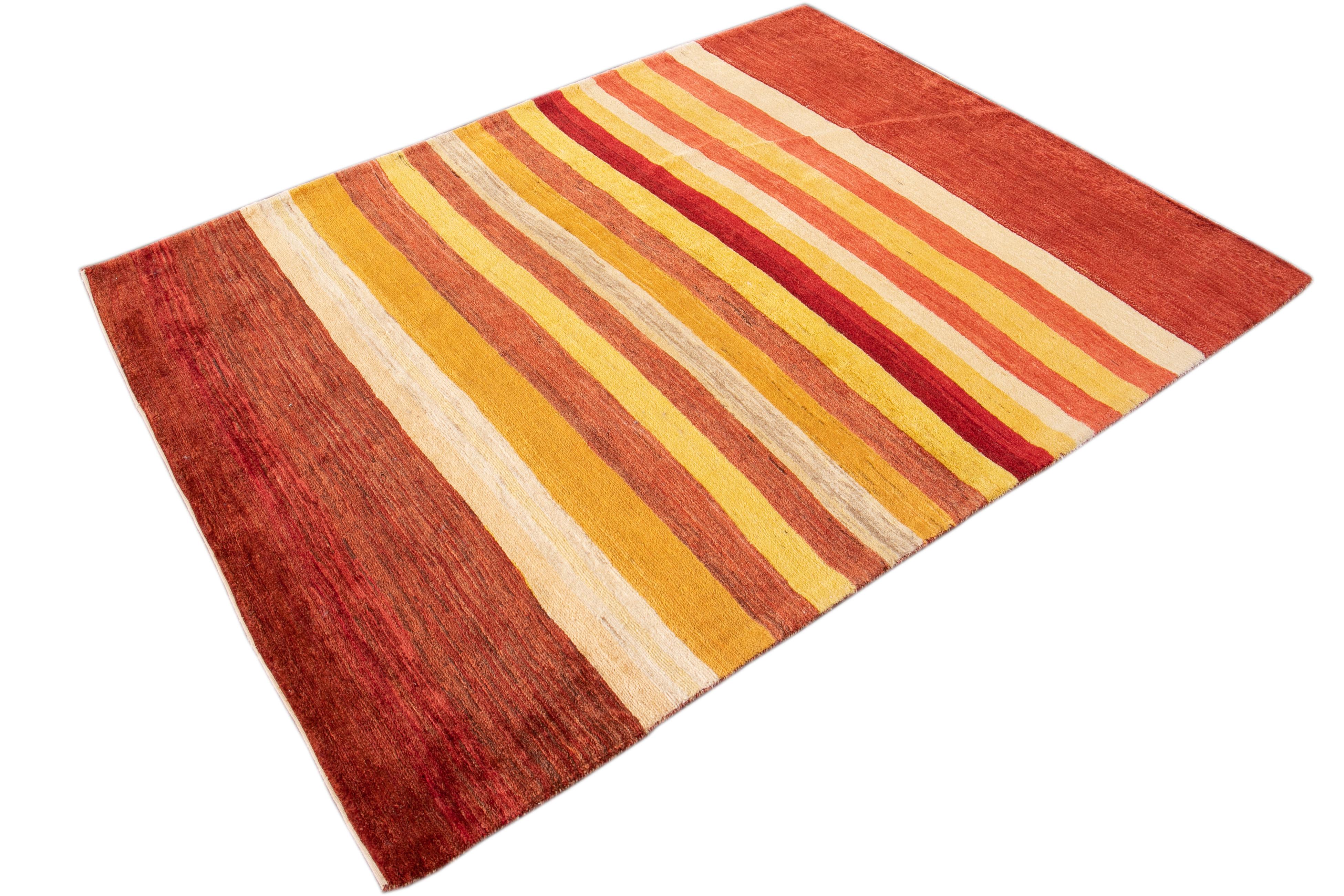 Beautiful contemporary 21st century Persian Gabbeh rug, with a rust/burnt orange field, ivory and yellow accents in a striped design.
This rug measures 5' 2